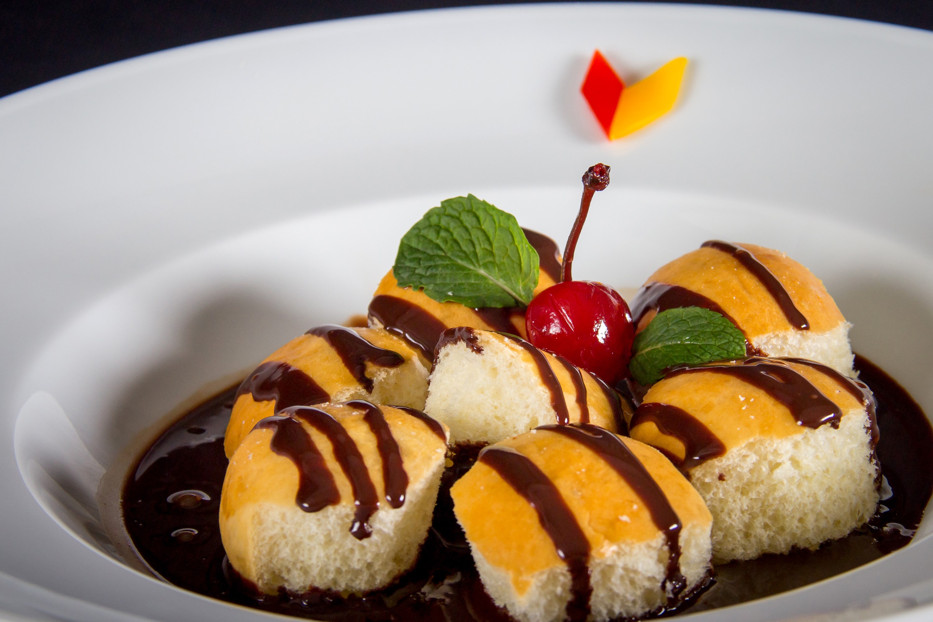 Chocolate drizzled buns with cherry and mint garnish HD Wallpaper