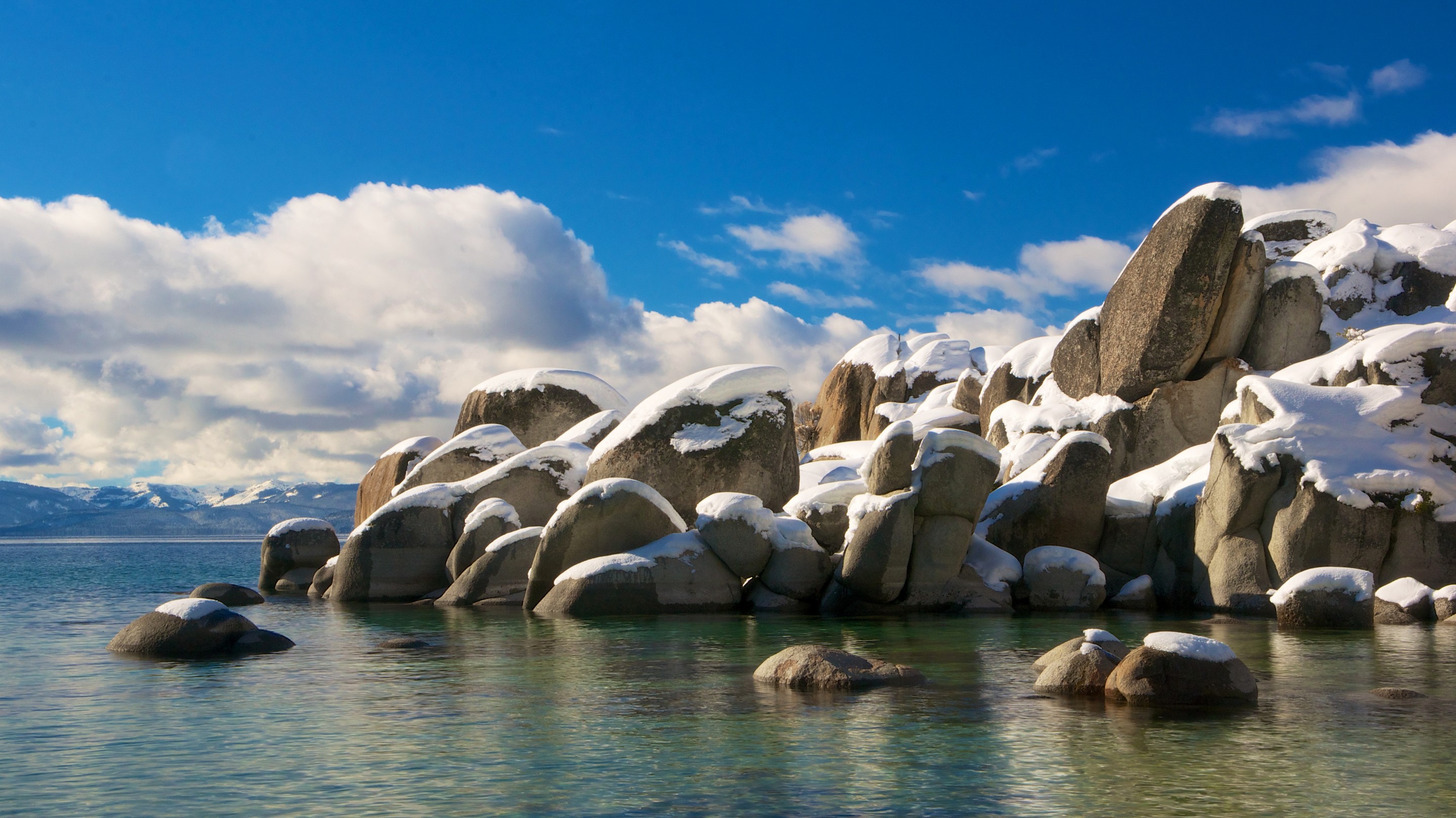 Snow-covered rocks in Lake Tahoe, California under a blue sky HD Wallpaper