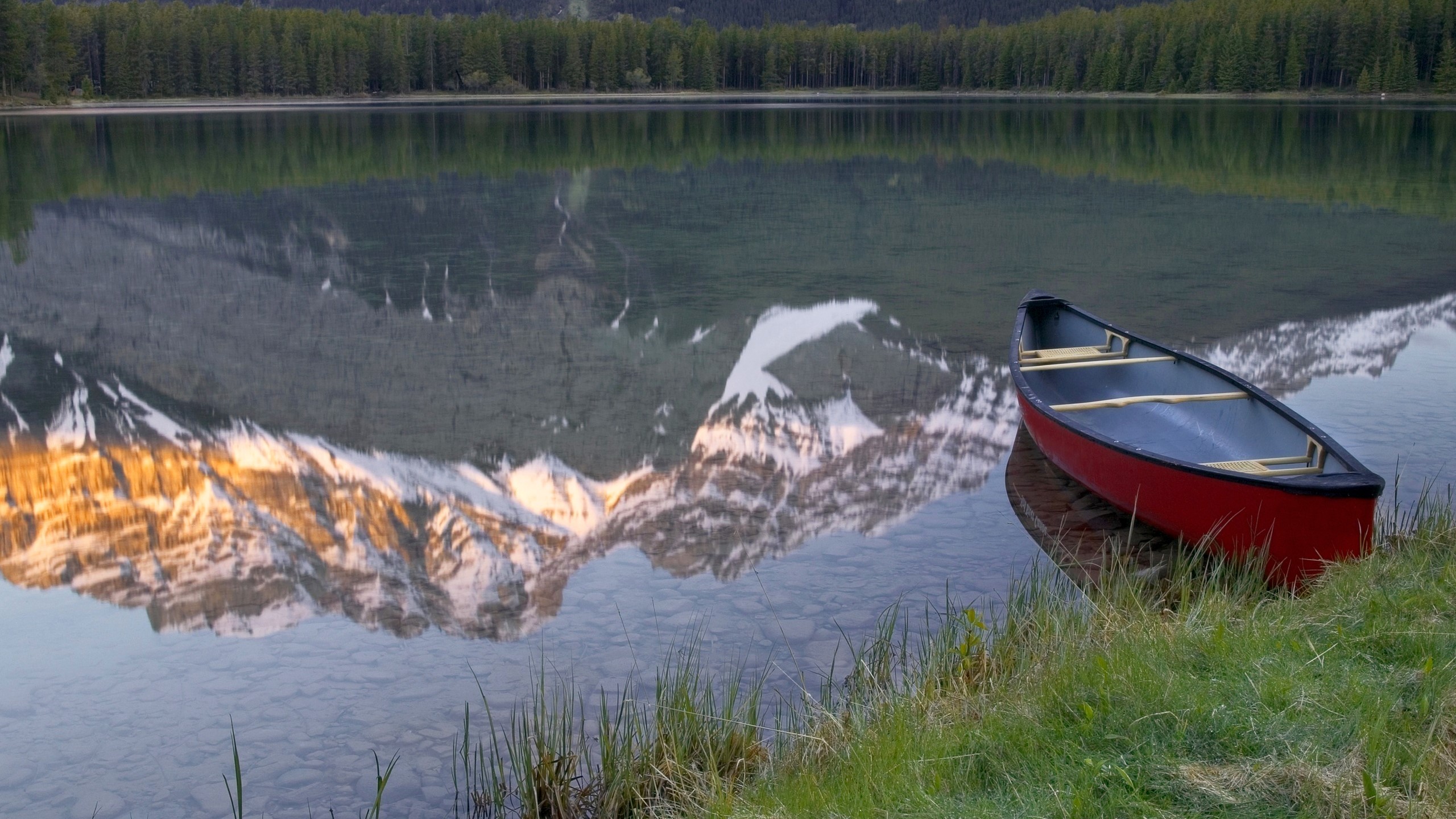 Red canoe on a calm lake with mountain reflection HD Wallpaper