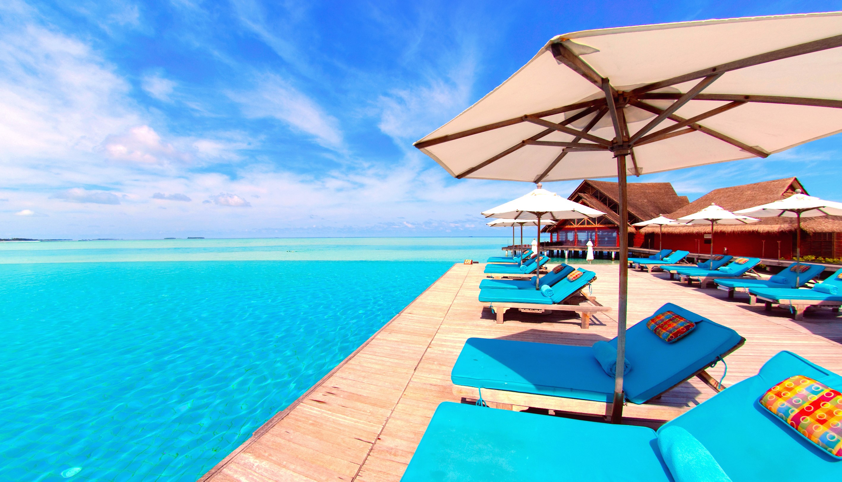 Infinity pool and sun loungers at a tropical resort HD Wallpaper