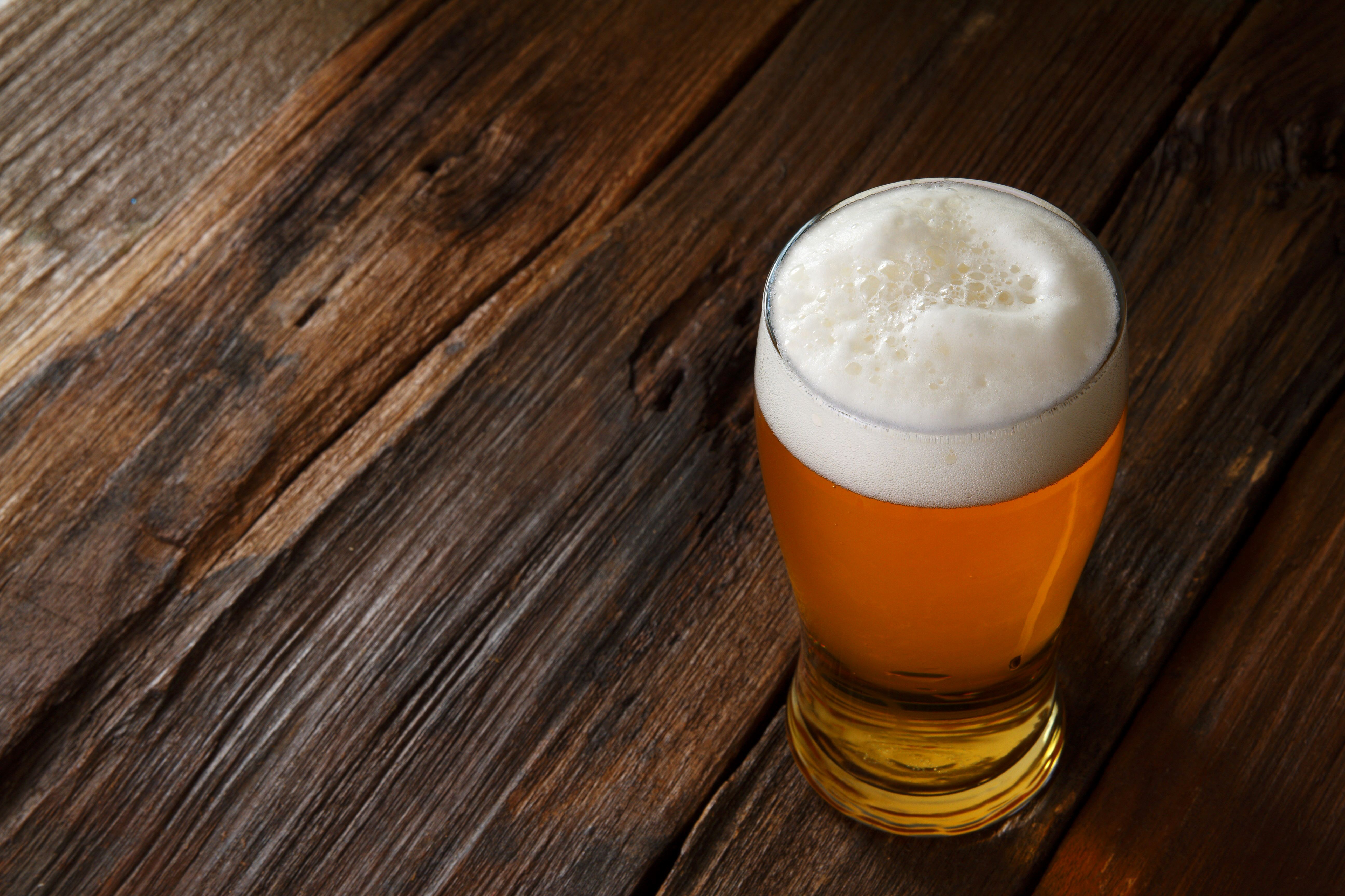 Beer in a highball glass on a wooden table HD Wallpaper