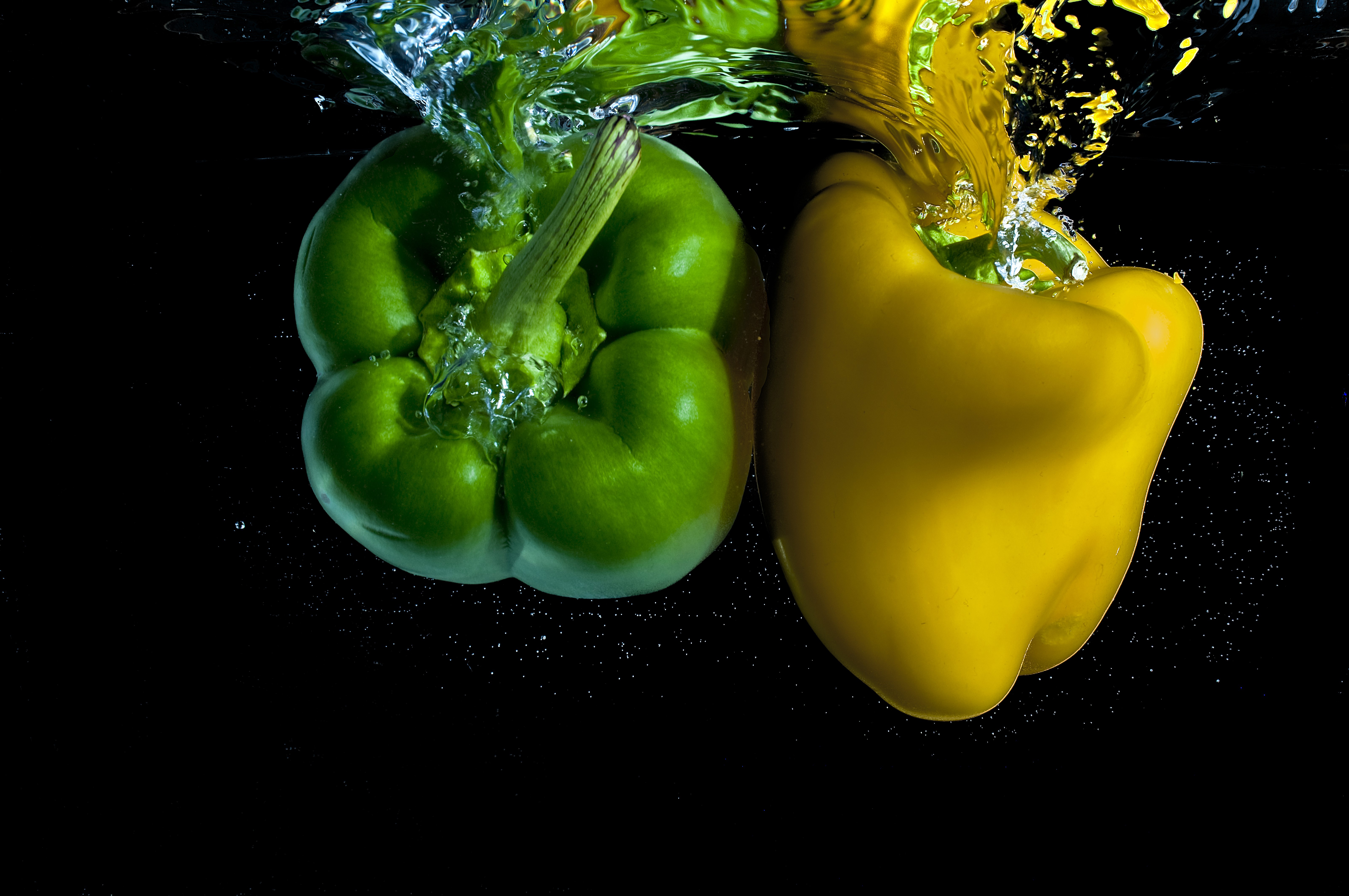 Green and yellow bell peppers splashing in water HD Wallpaper