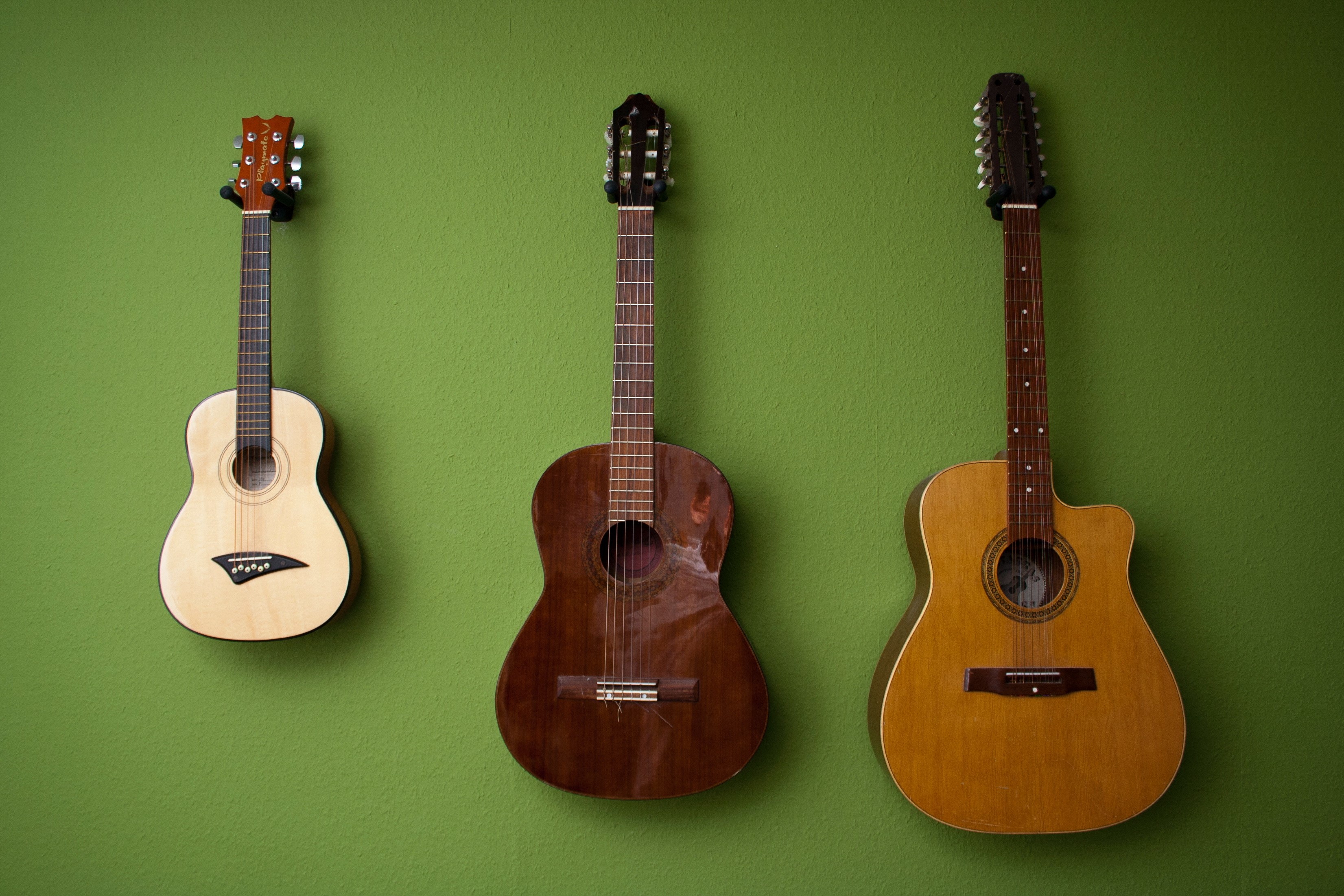 Three guitars hanging on a green wall HD Wallpaper