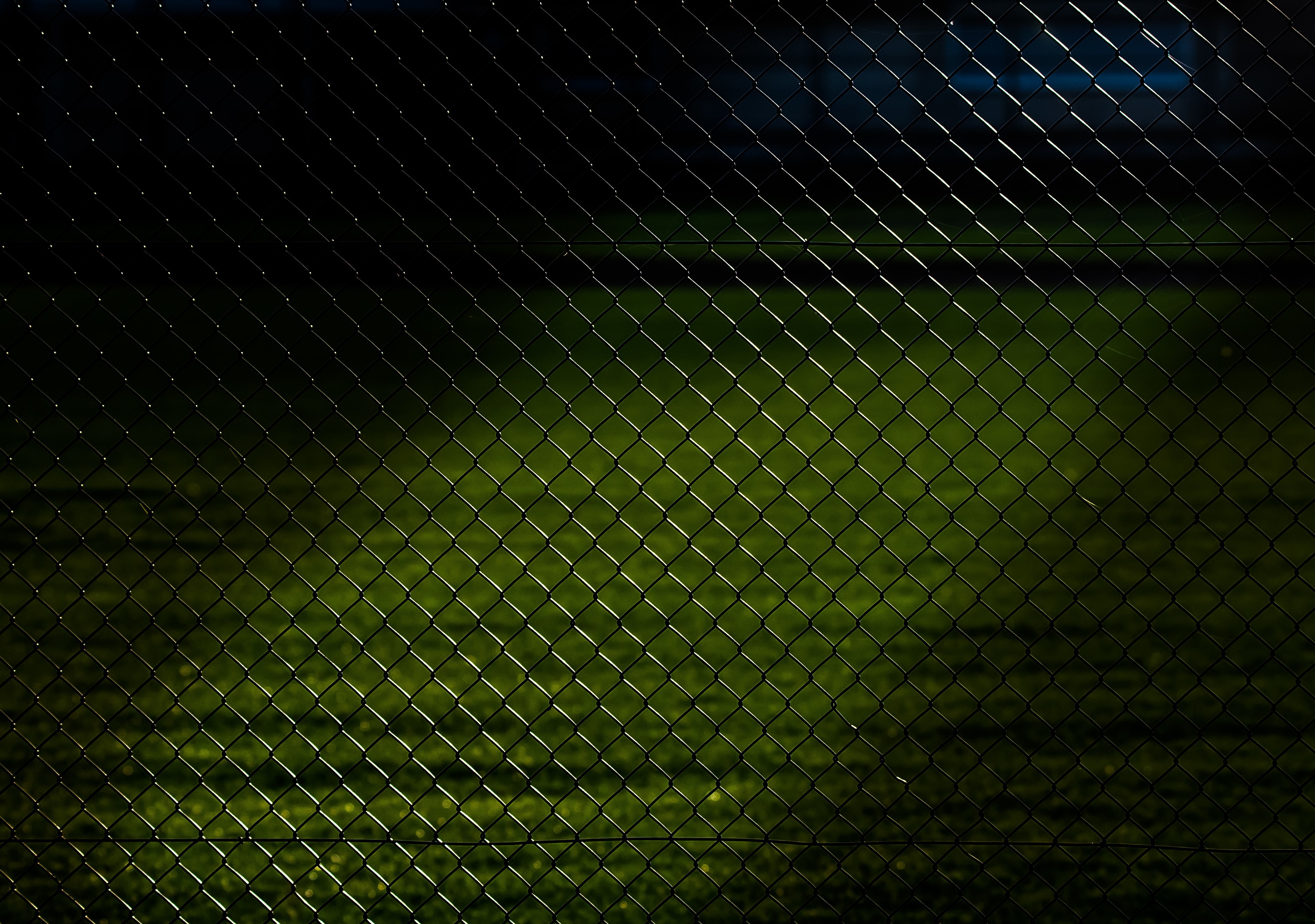 Chain link fence over green field at night HD Wallpaper