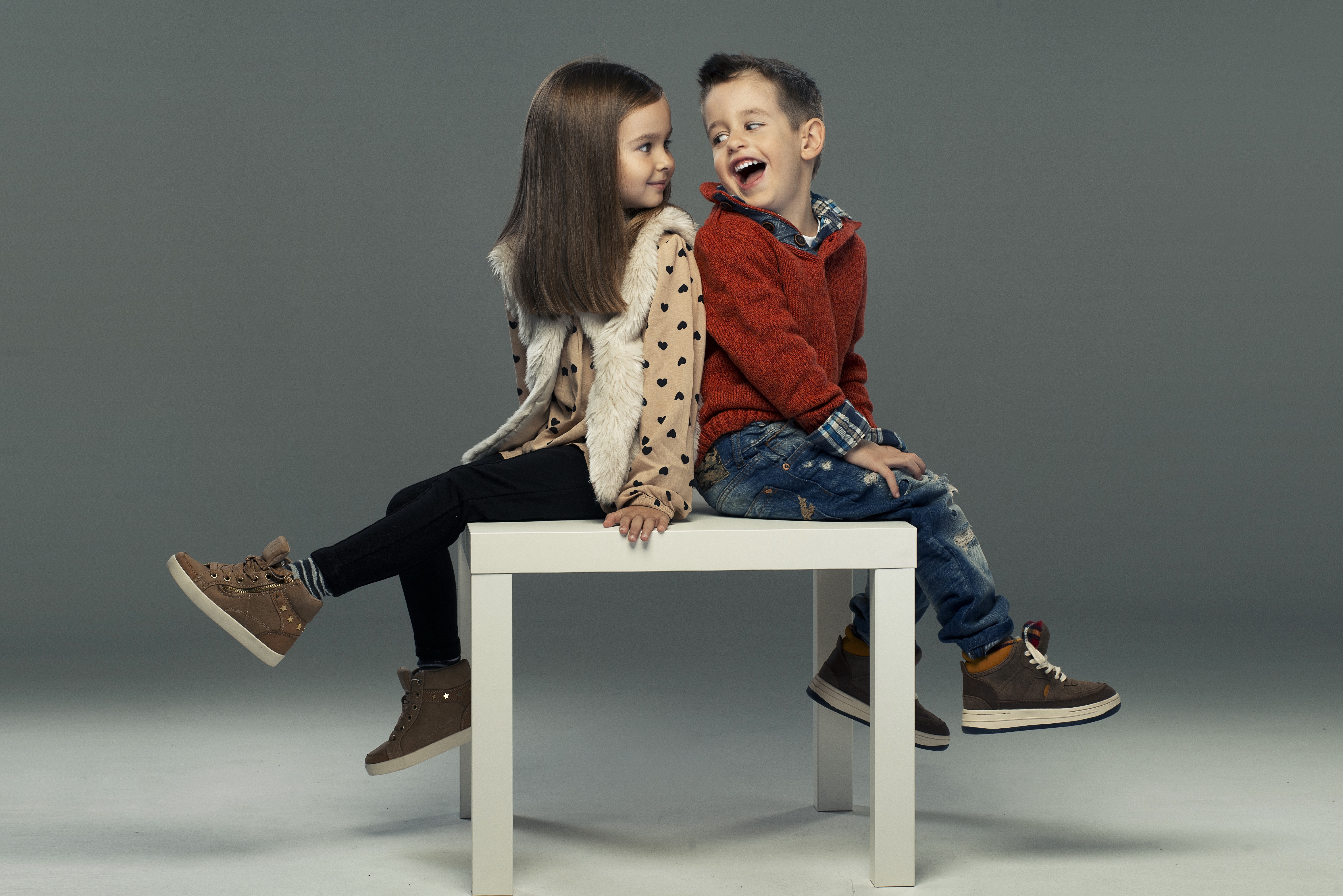 Boy and girl sitting on a white table HD Wallpaper