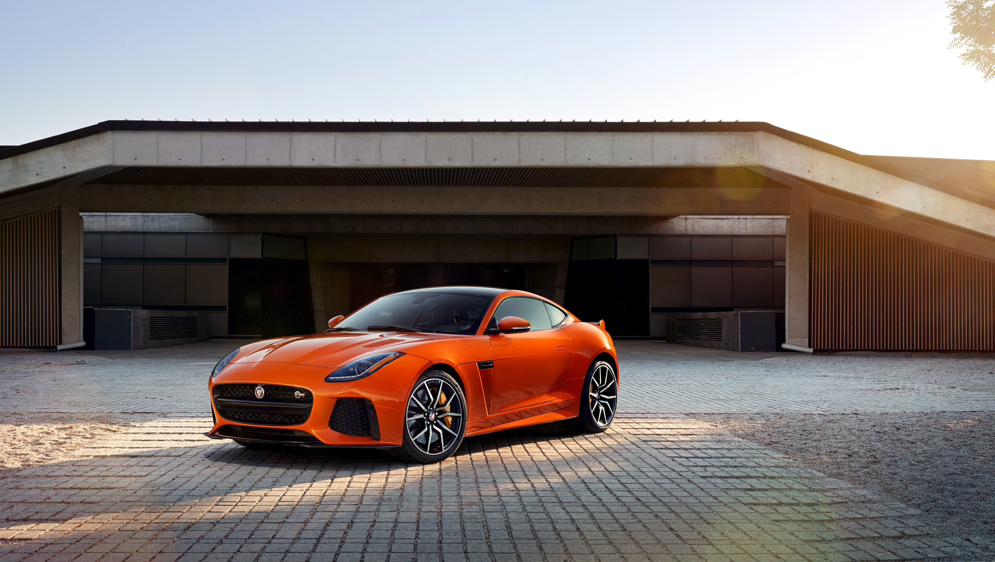 Orange Jaguar F-Type SVR parked in front of a modern building HD Wallpaper