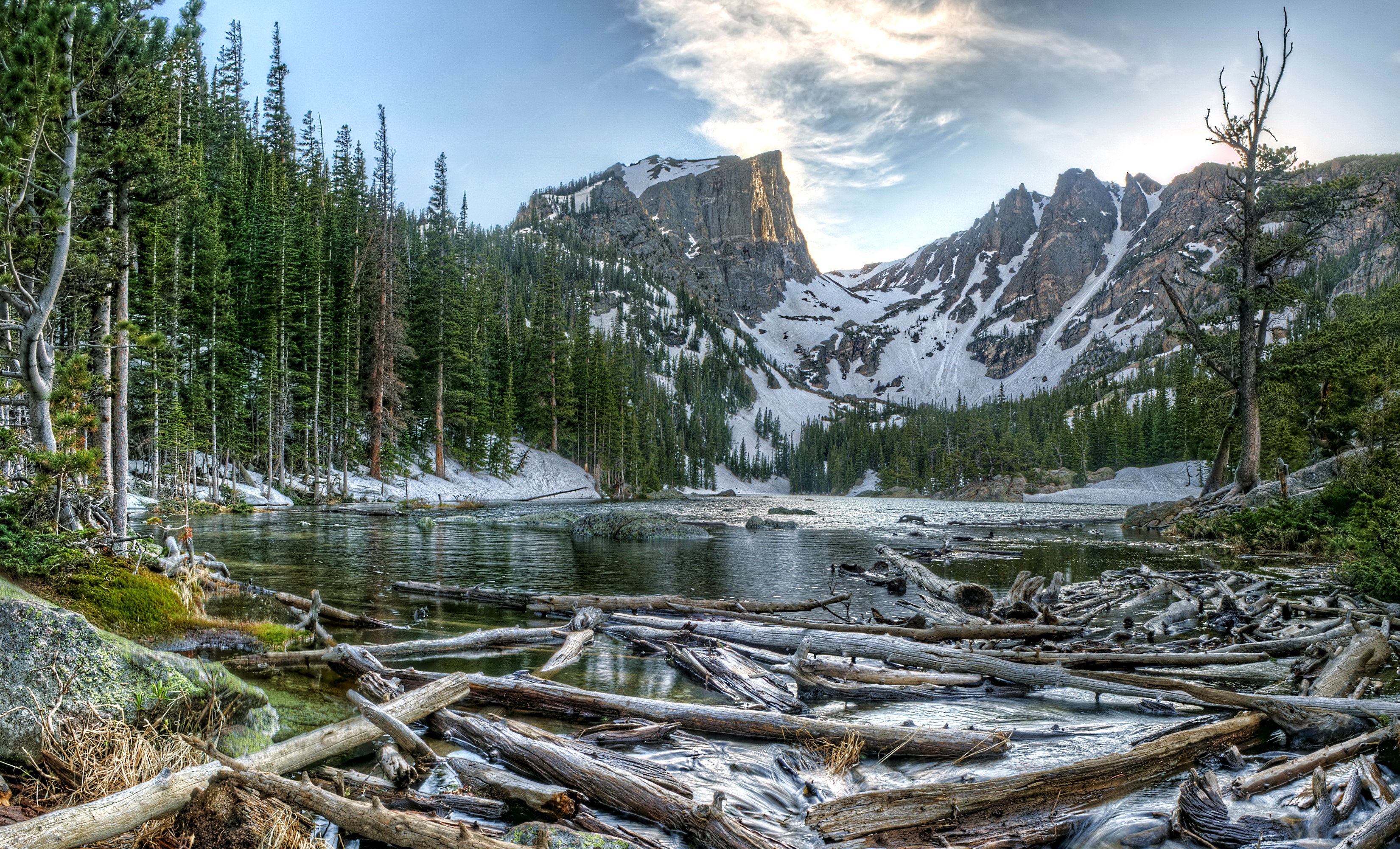 Rocky Mountains lake with snow-capped peaks and pine forest HD Wallpaper