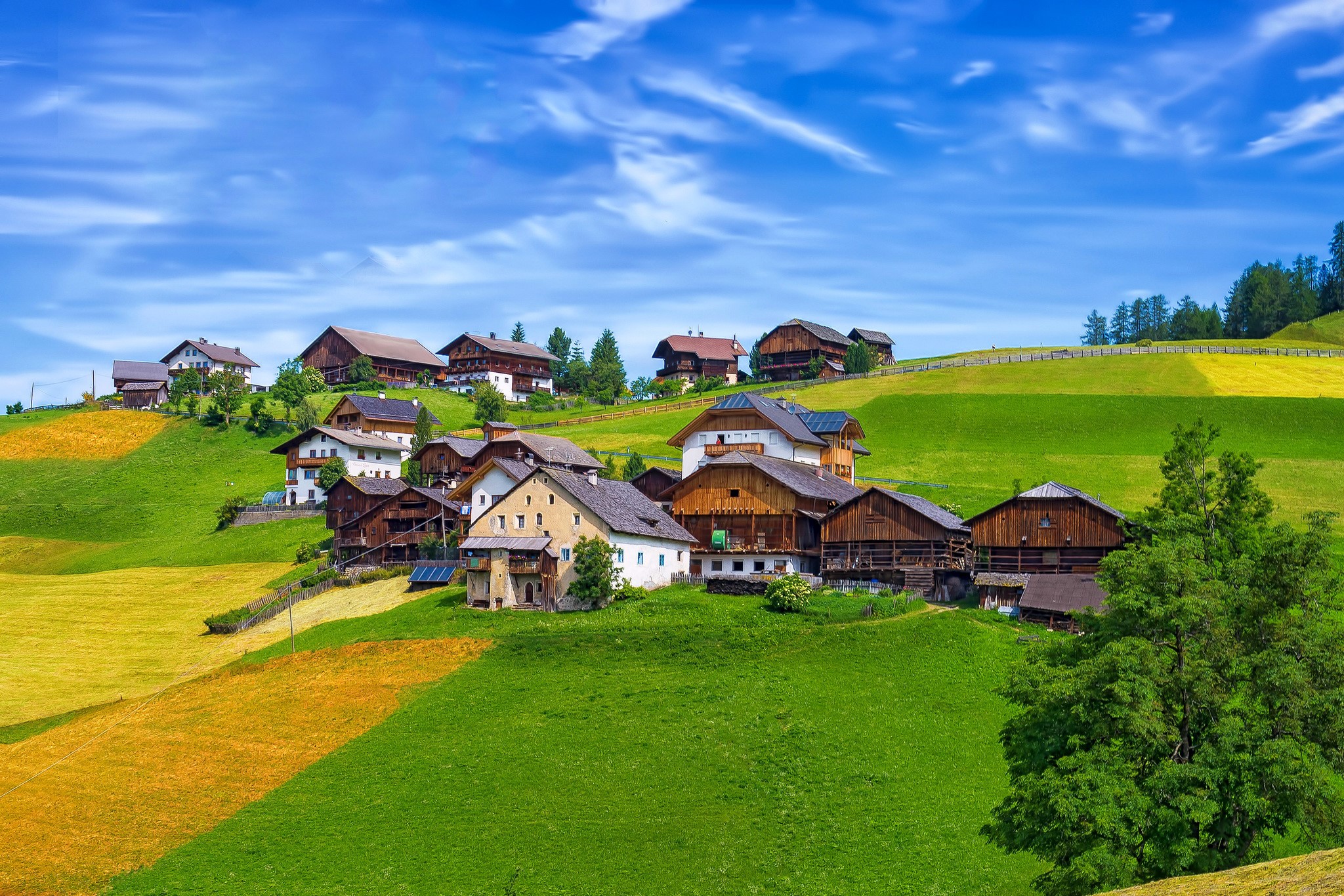 Houses on a grassy hillside in La Val, Italy HD Wallpaper
