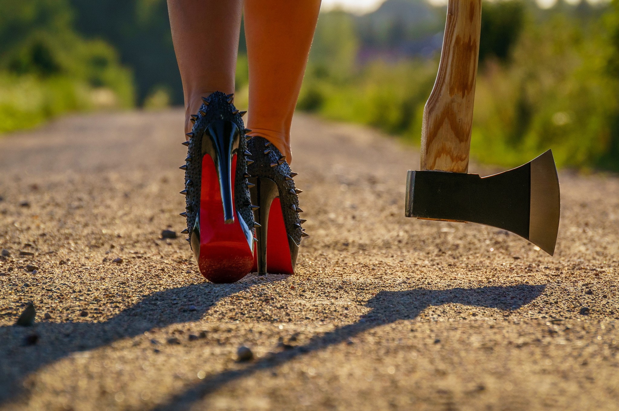 Woman in spiked heels and an axe on a dirt road HD Wallpaper