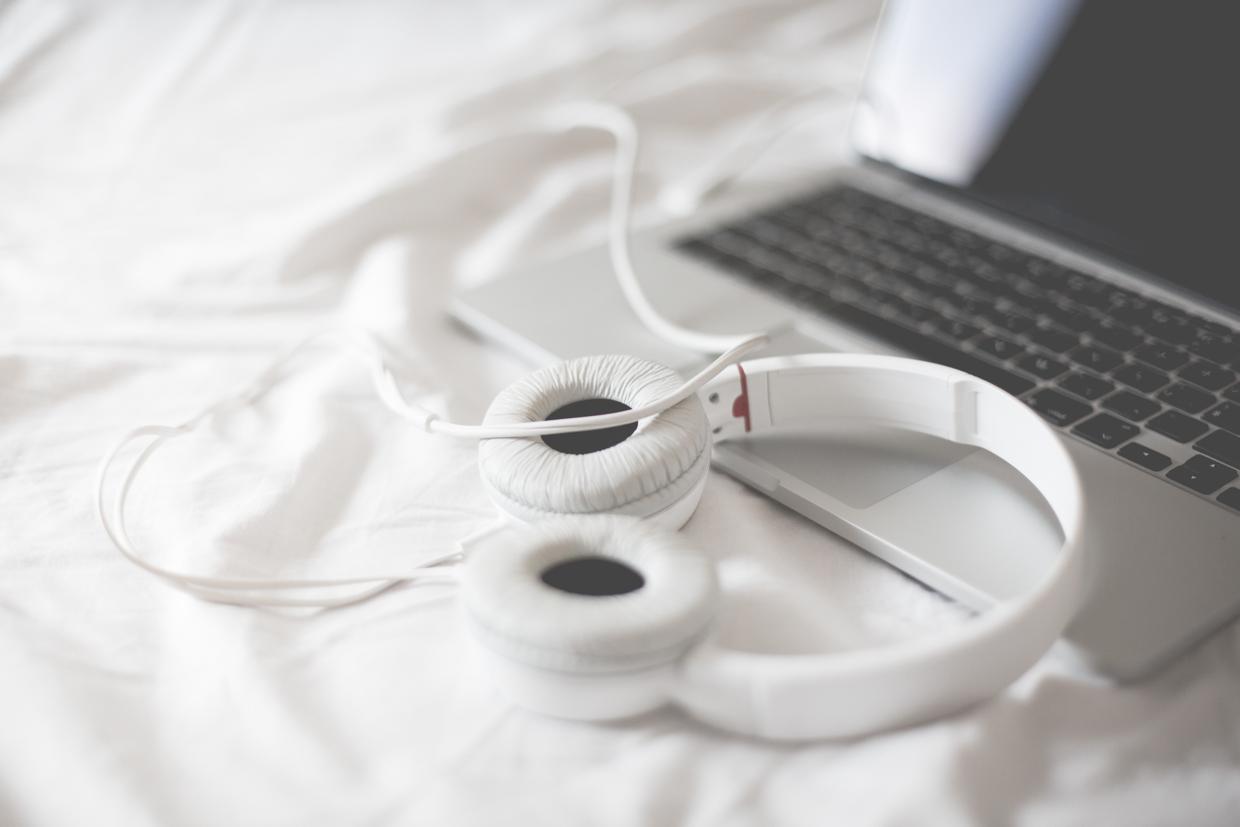 White Headphones and Laptop on White Bedding HD Wallpaper
