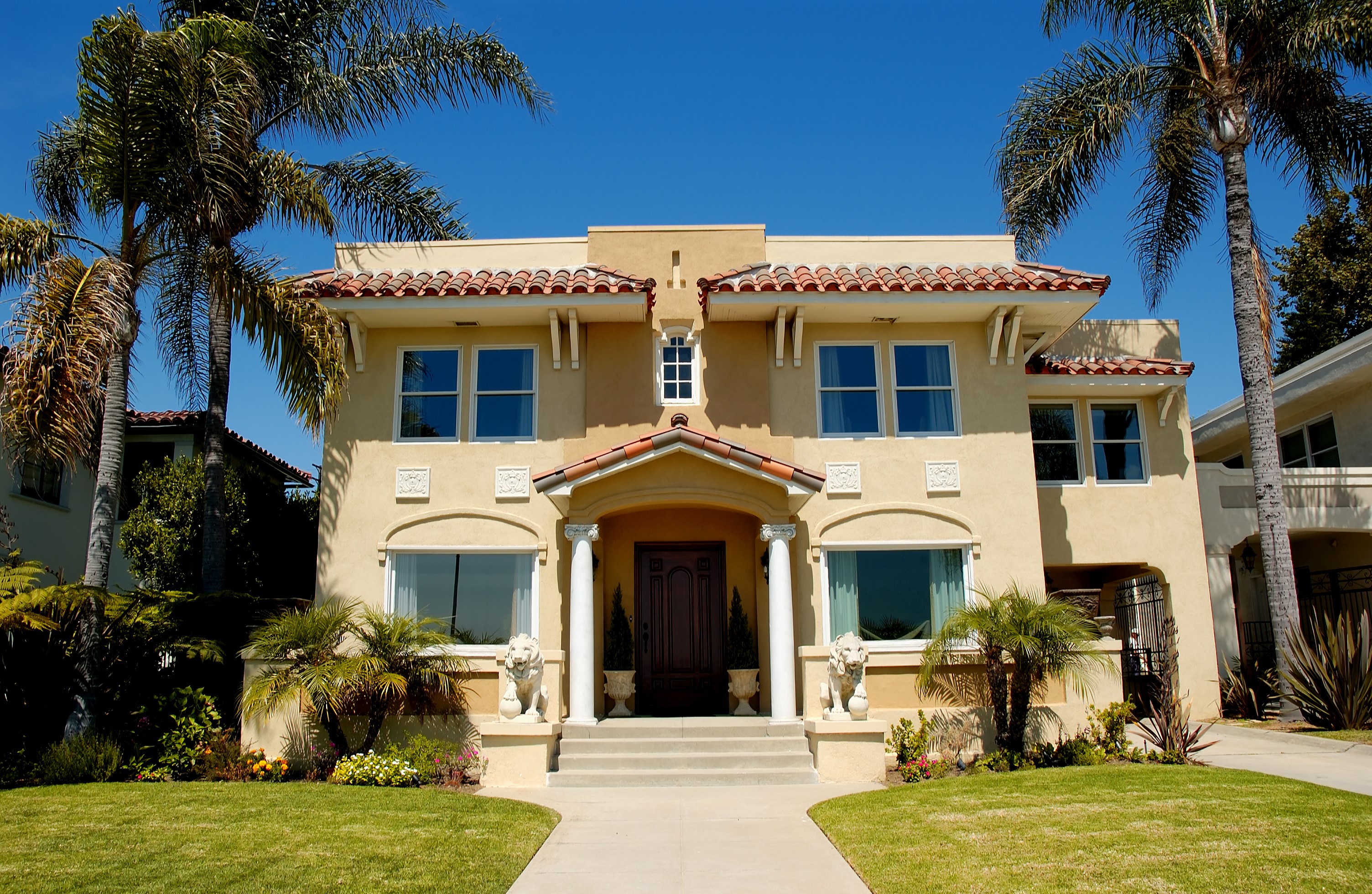 Yellow Mediterranean-style house with palm trees and lawn HD Wallpaper