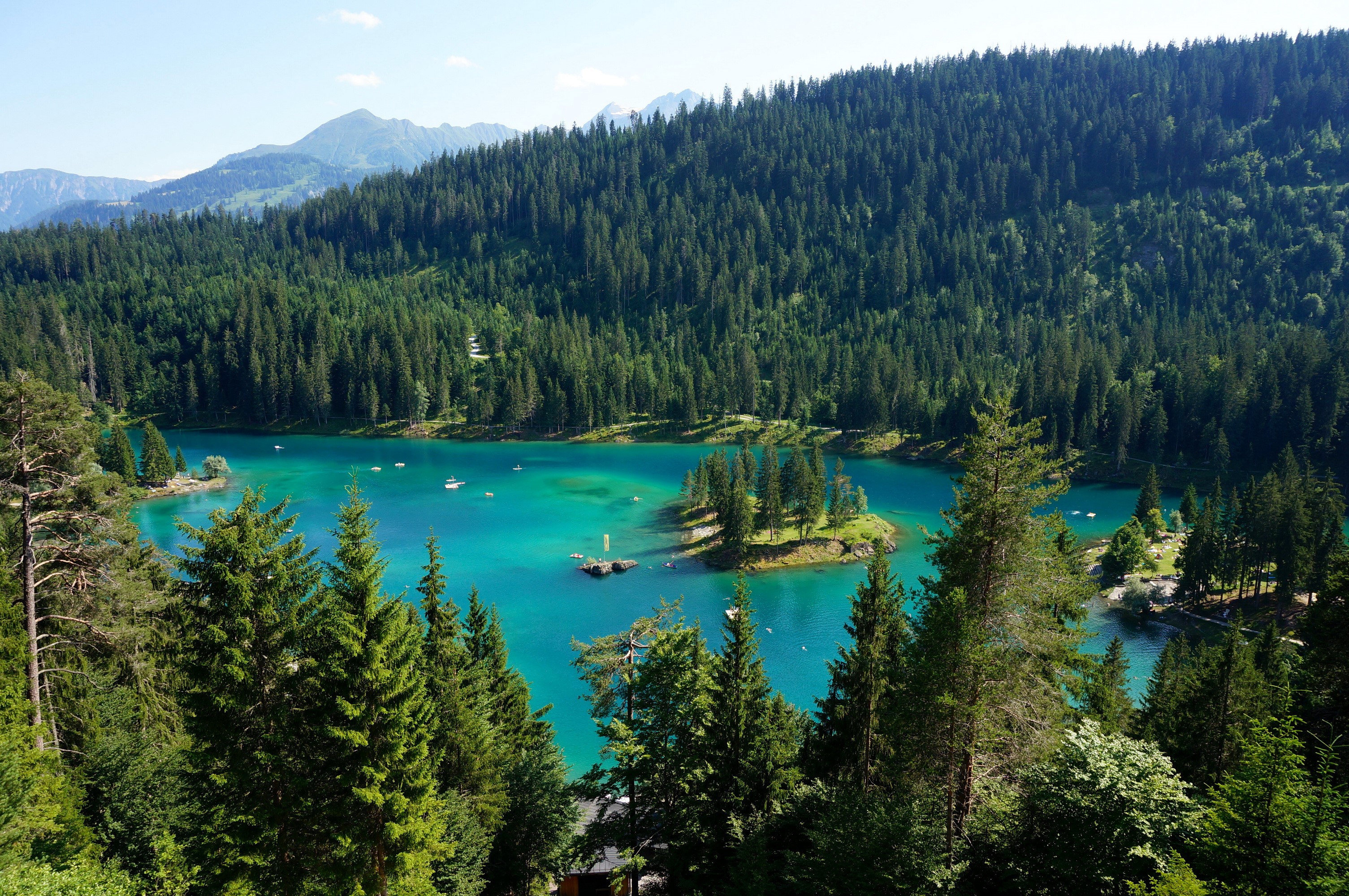 Turquoise lake surrounded by pine forests in Switzerland HD Wallpaper
