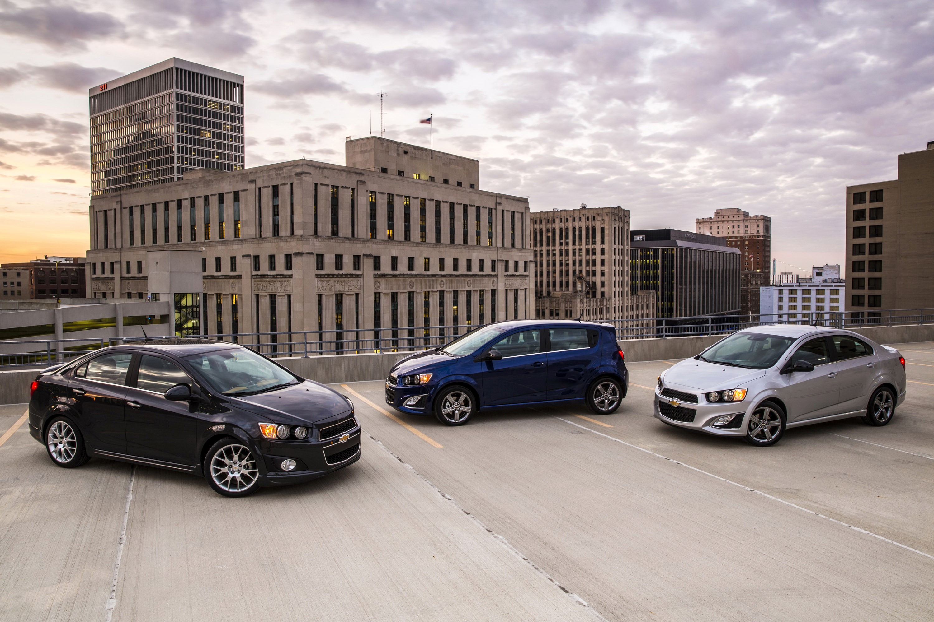 Three Chevrolet Sonic cars on a rooftop parking lot HD Wallpaper