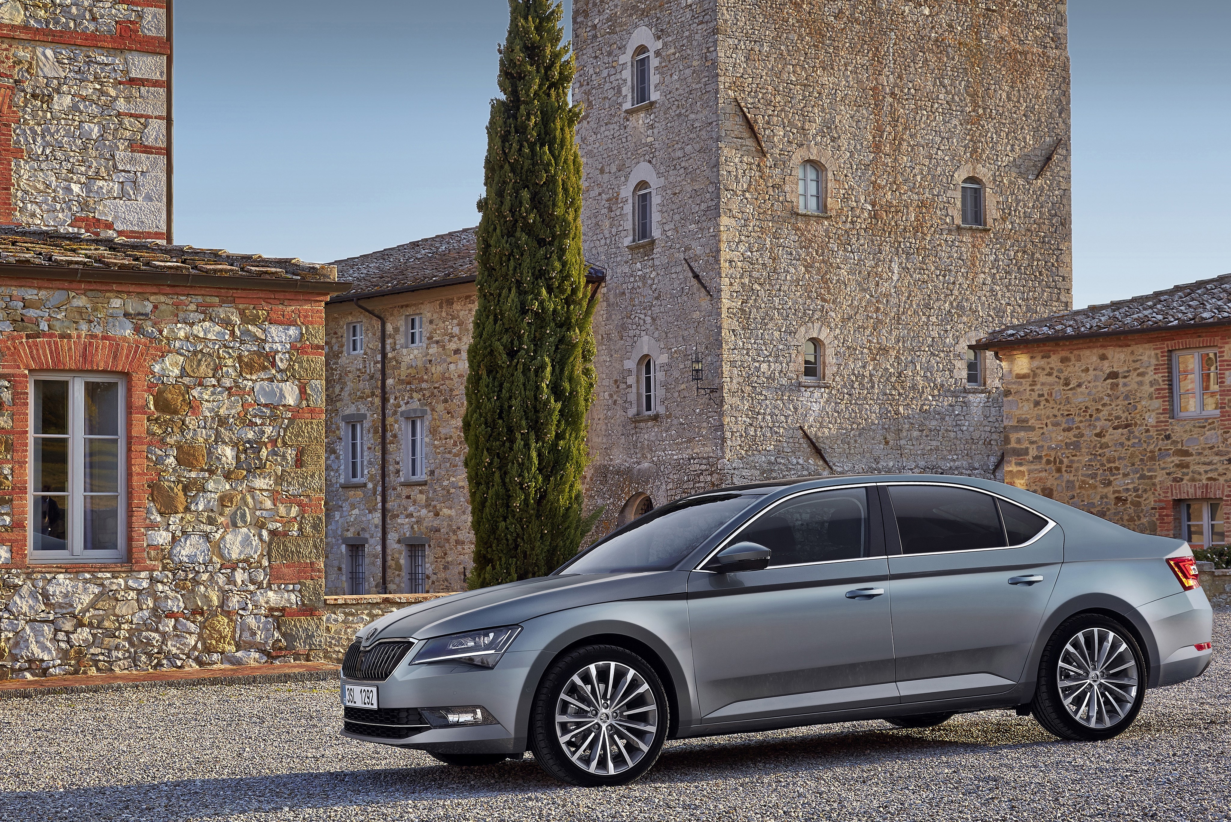 Skoda Superb parked near stone buildings HD Wallpaper