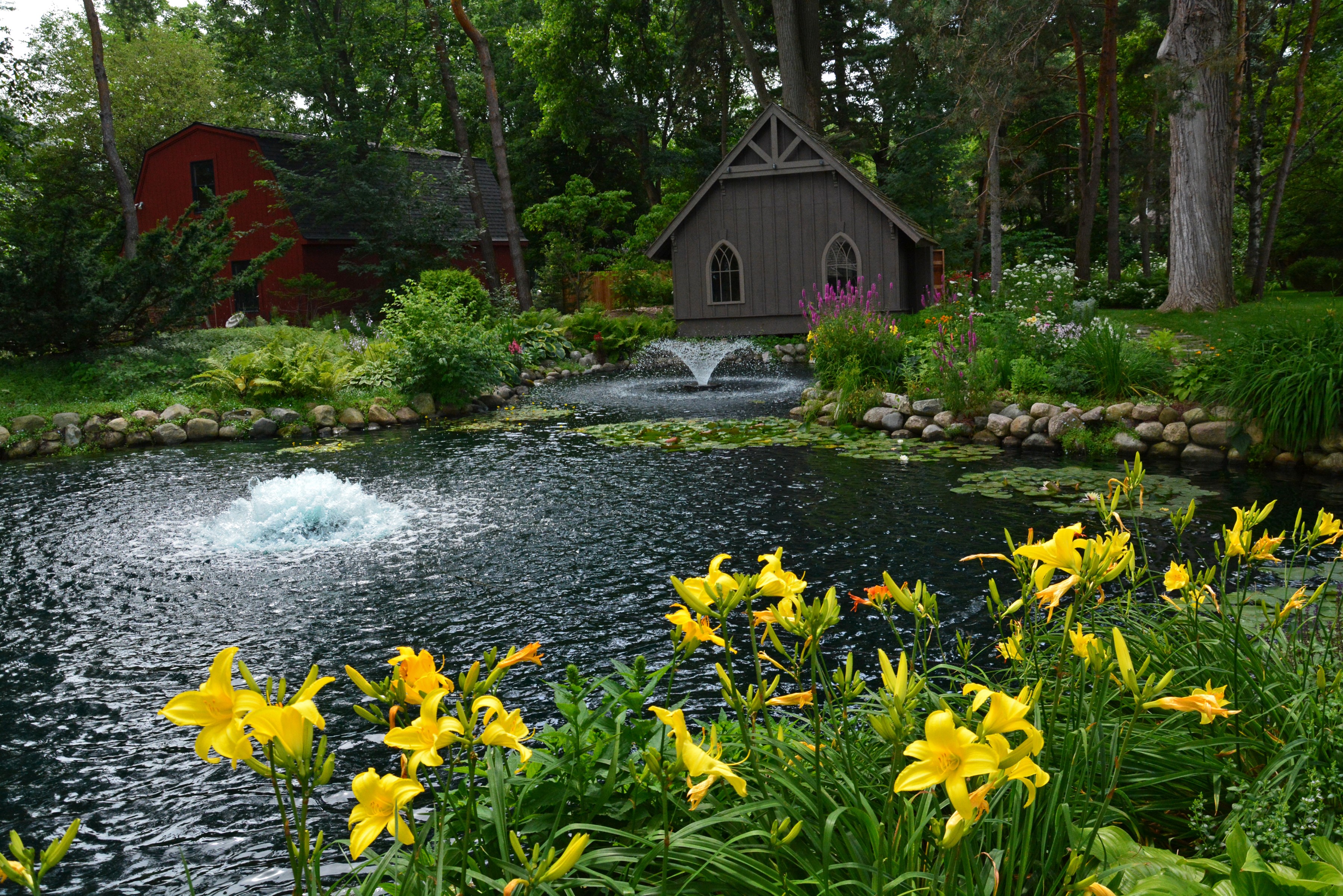 Pond with fountains and lilies in a garden HD Wallpaper