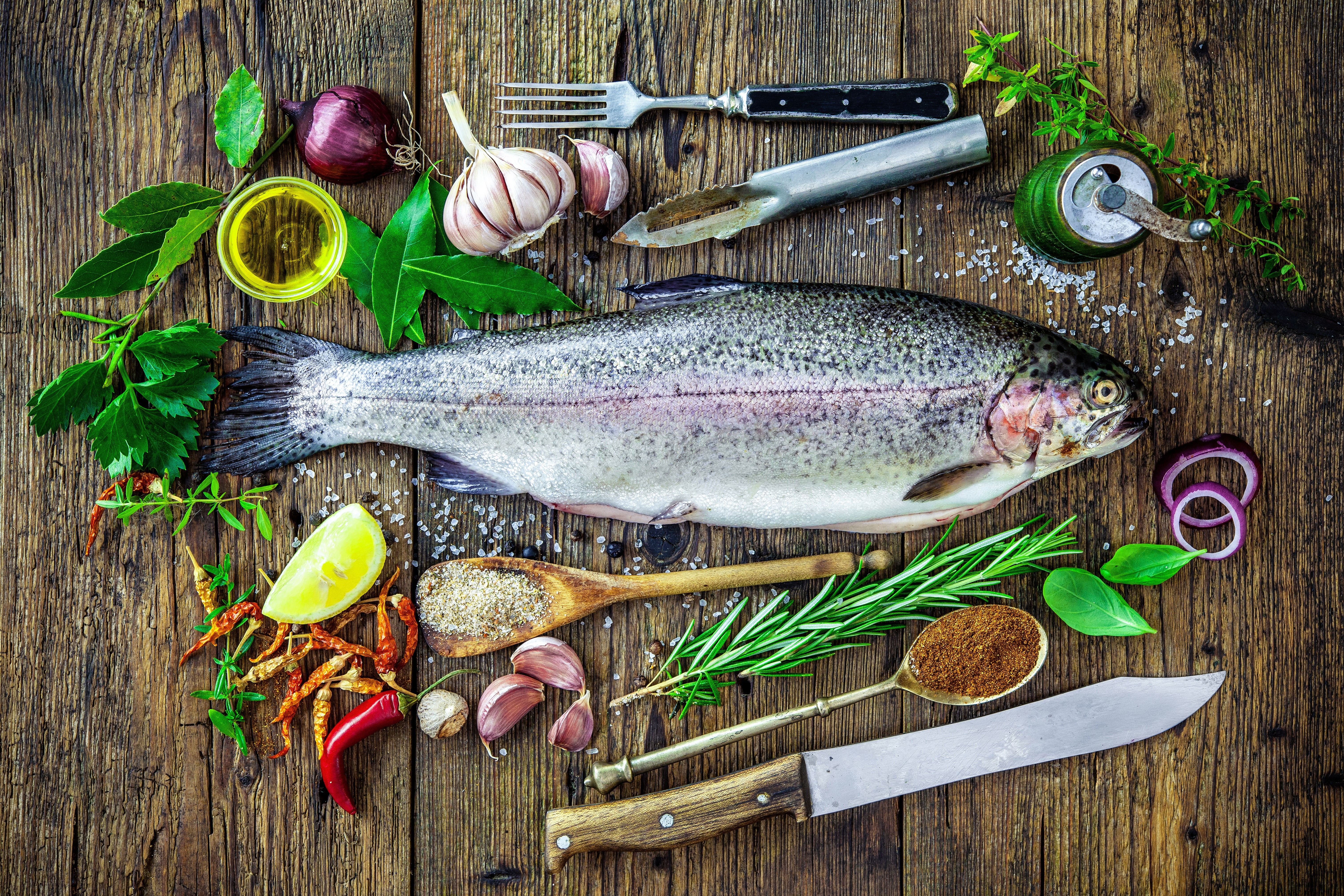 Whole trout with herbs, spices, and vegetables on wooden table HD Wallpaper