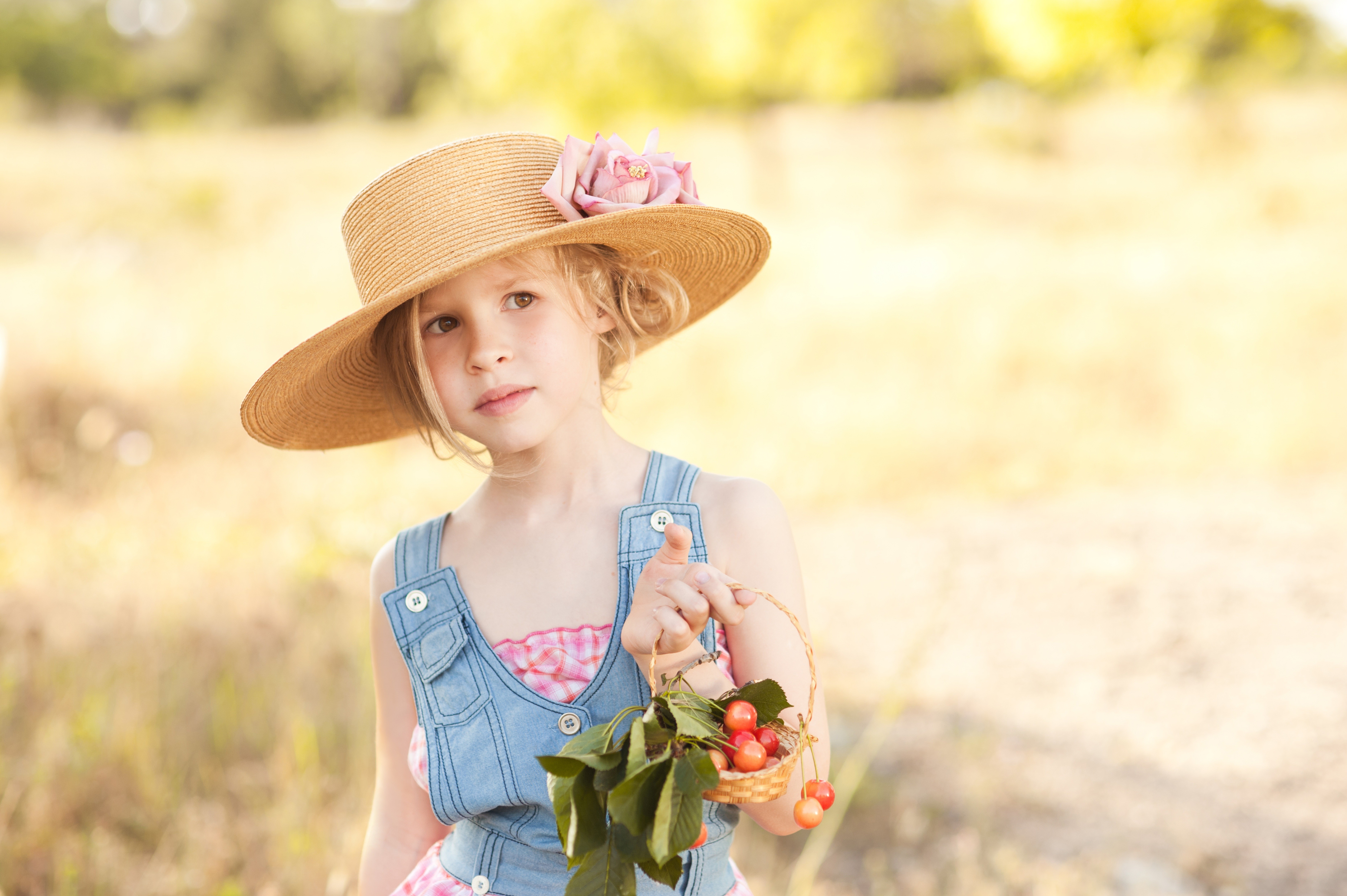 Little girl in a straw hat holding cherries HD Wallpaper