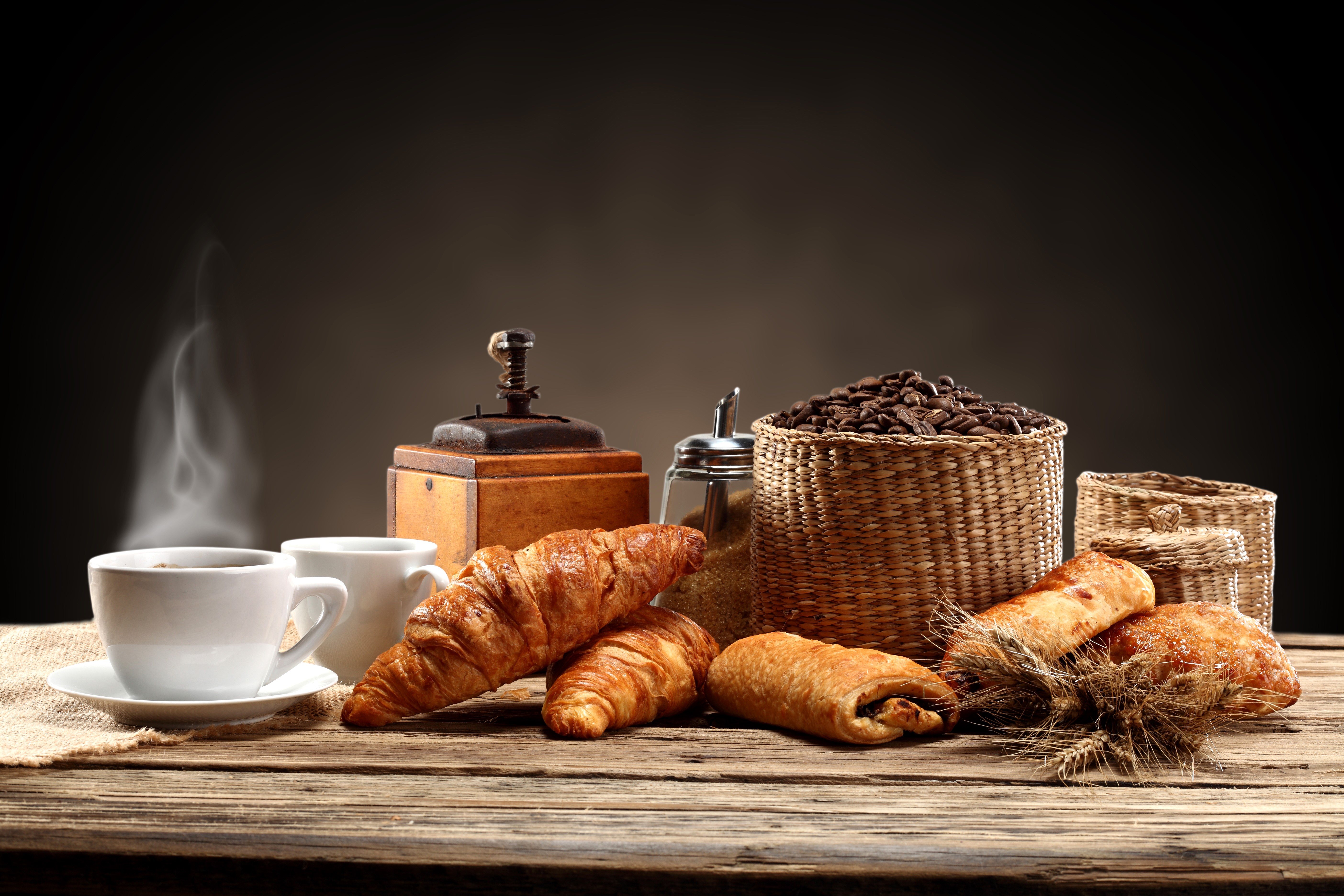 Coffee cups, croissants, and coffee beans on a wooden table HD Wallpaper