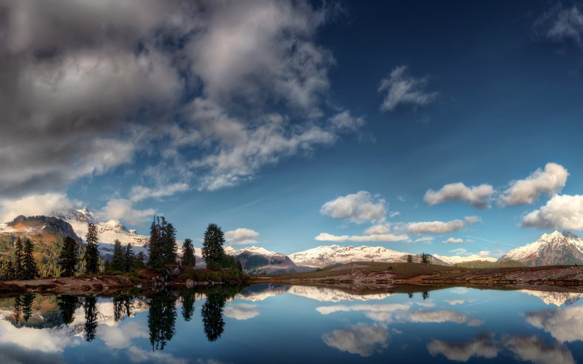 Mountain lake reflecting snow-capped mountains and cloudy sky HD Wallpaper