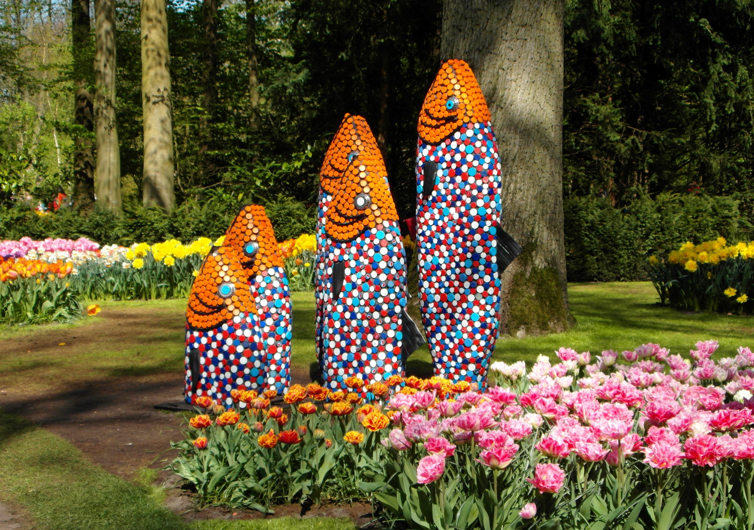 Fish sculptures in a park with tulips HD Wallpaper