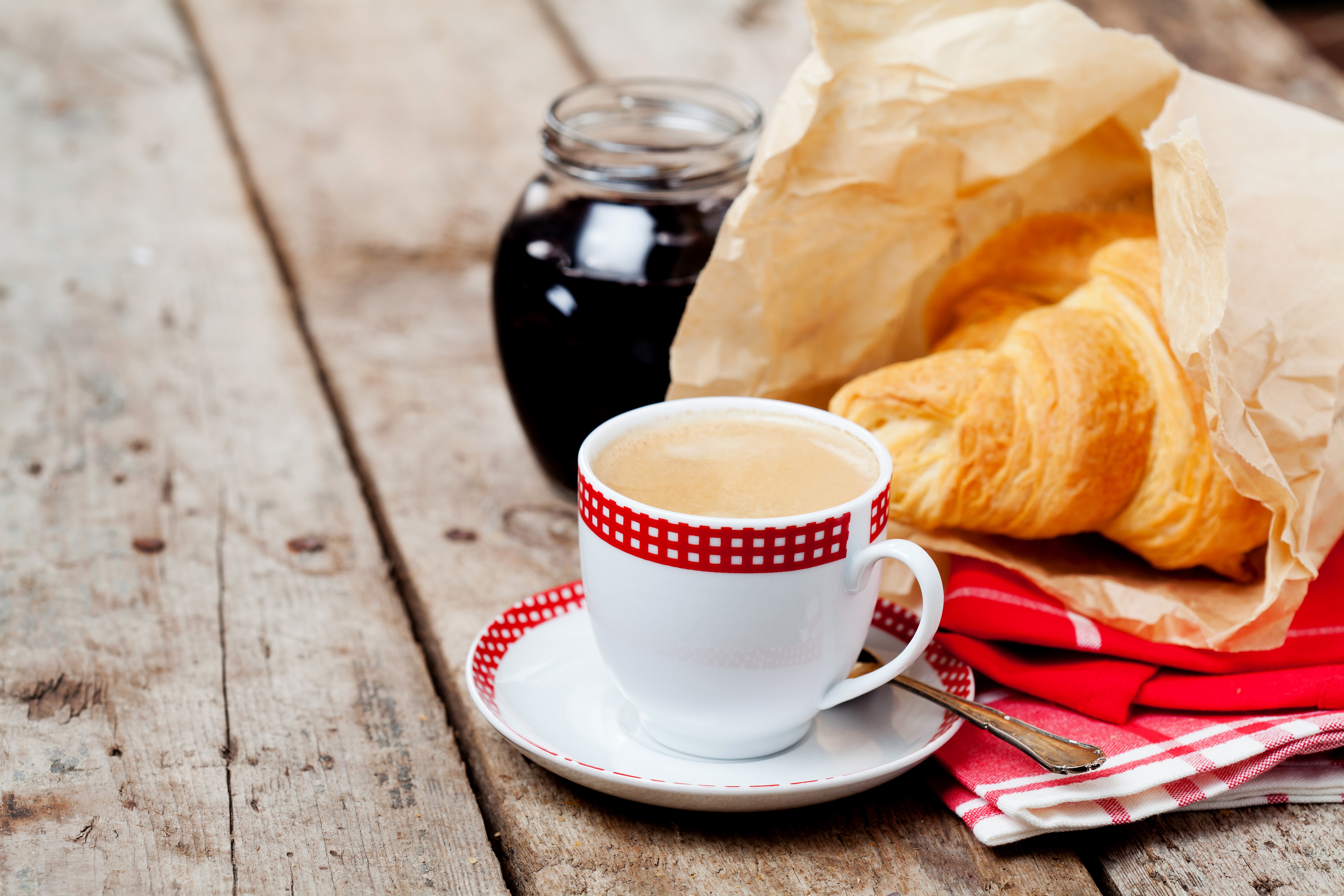 Coffee cup, croissant, and jam jar on wooden table HD Wallpaper