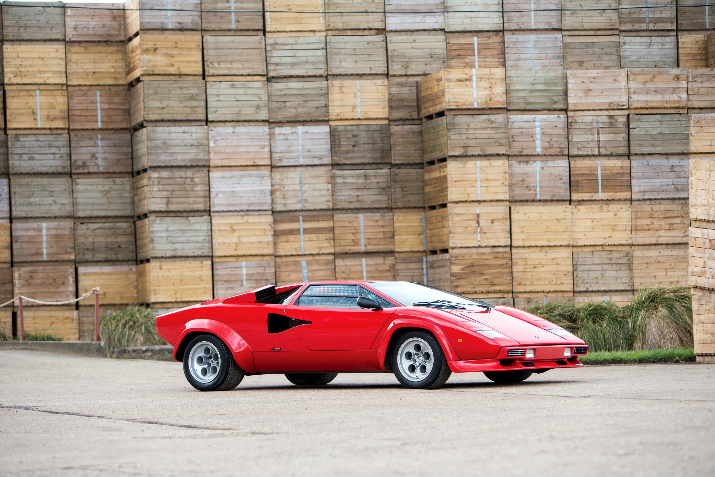 Red Lamborghini Countach parked in front of wooden crates HD Wallpaper
