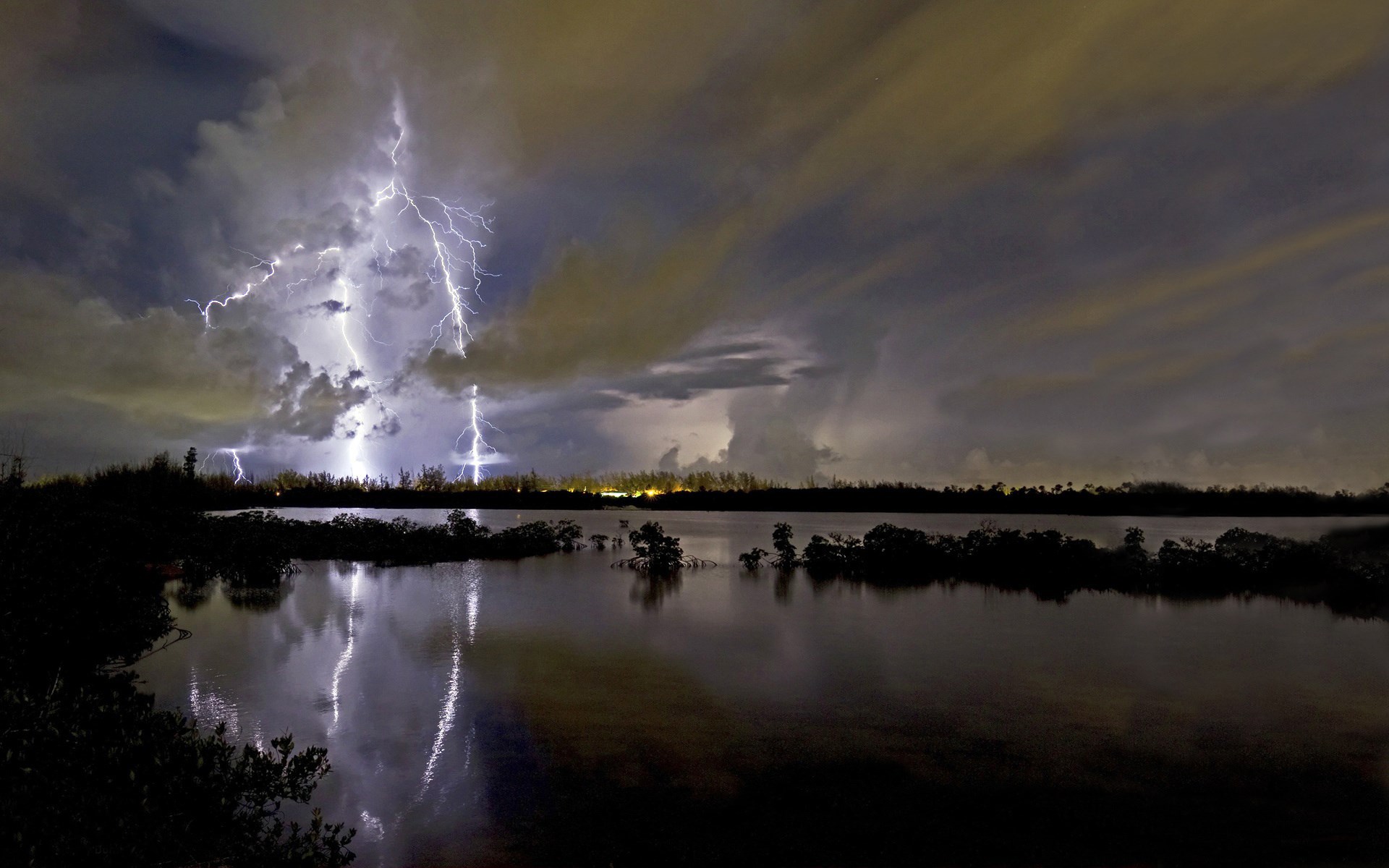 Lightning strikes over a body of water at night HD Wallpaper