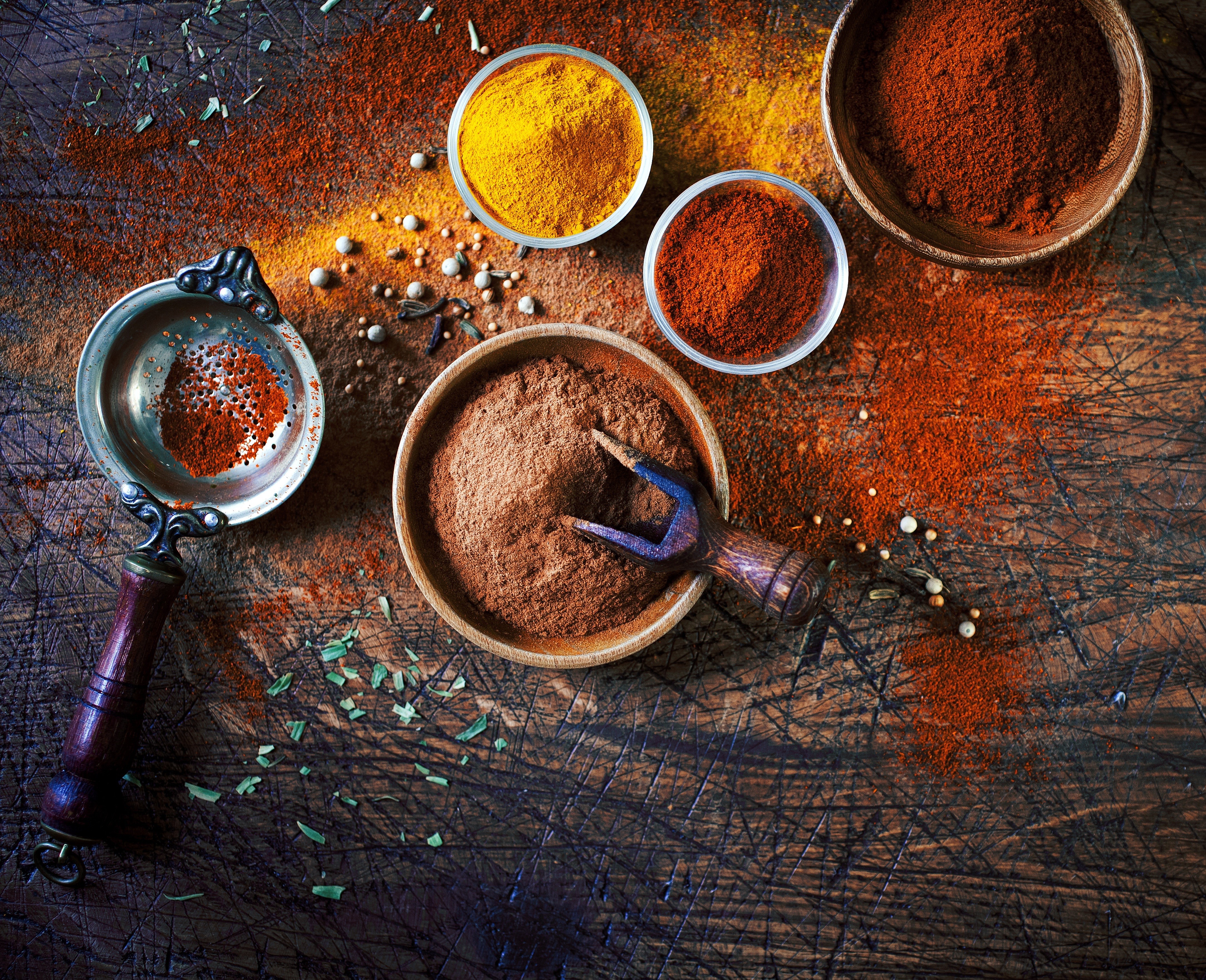 Spices in bowls and sieve on wooden surface HD Wallpaper