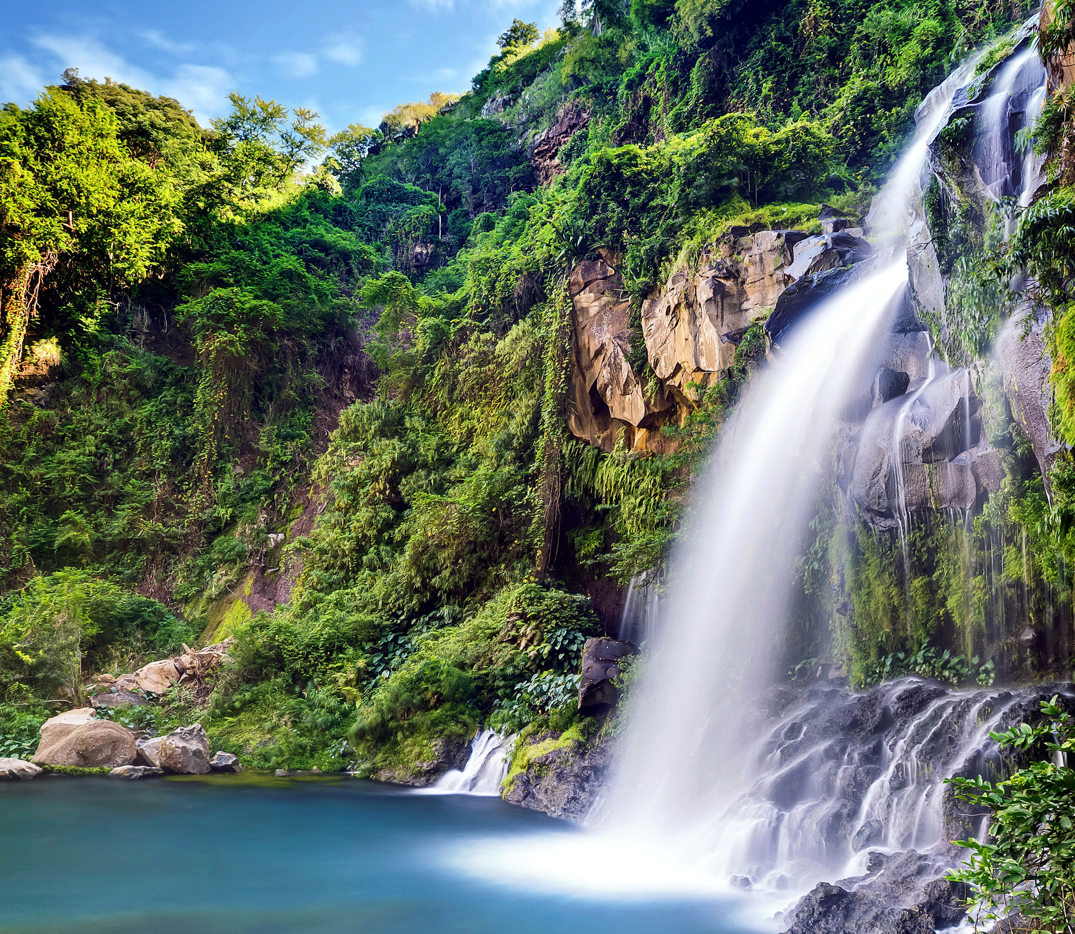 Waterfall cascading down a rocky cliff into a blue pool HD Wallpaper