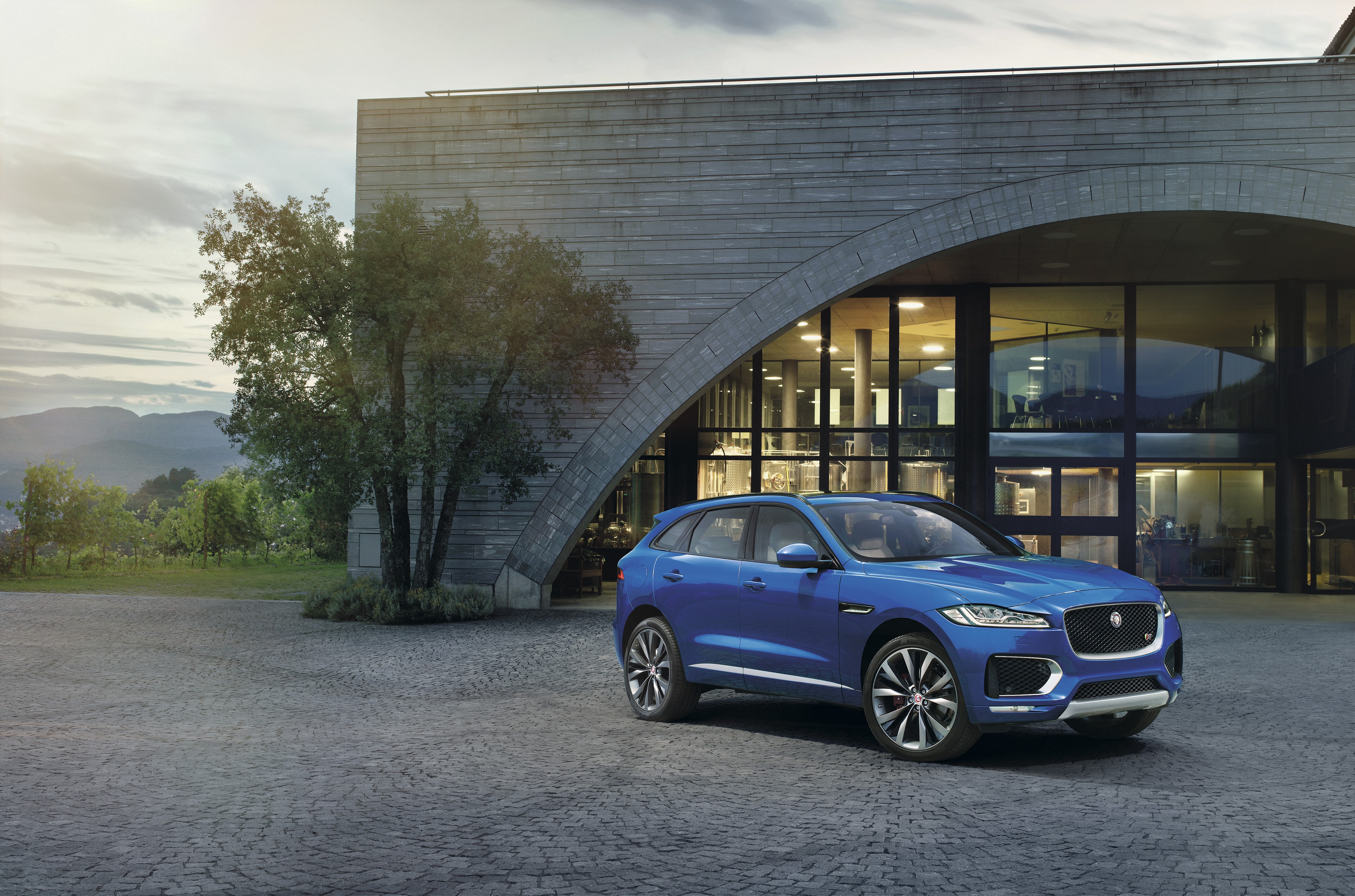 Blue Jaguar F-Pace S parked in front of modern building HD Wallpaper