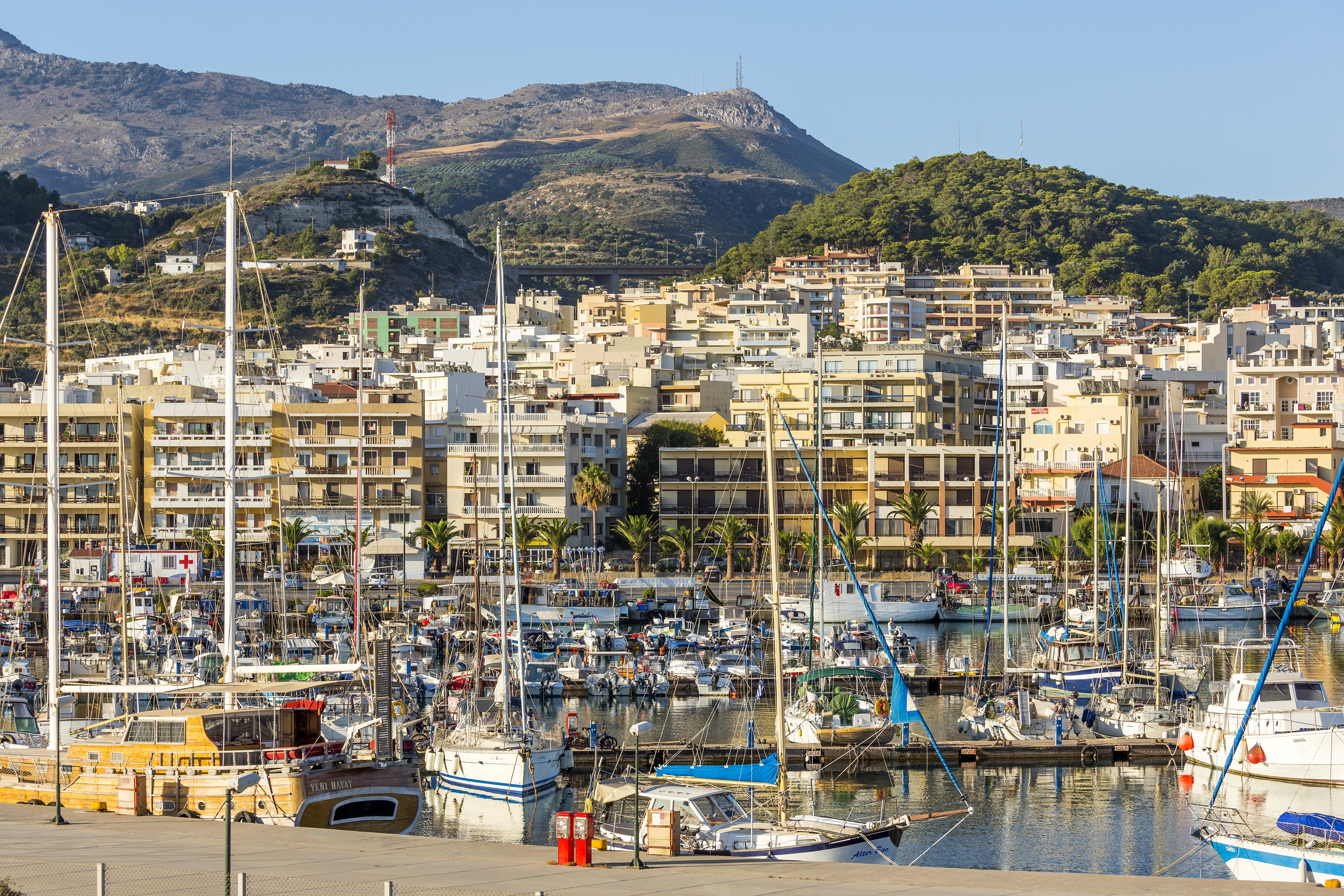 Boats in a harbor with buildings and mountains in Crete, Greece HD Wallpaper