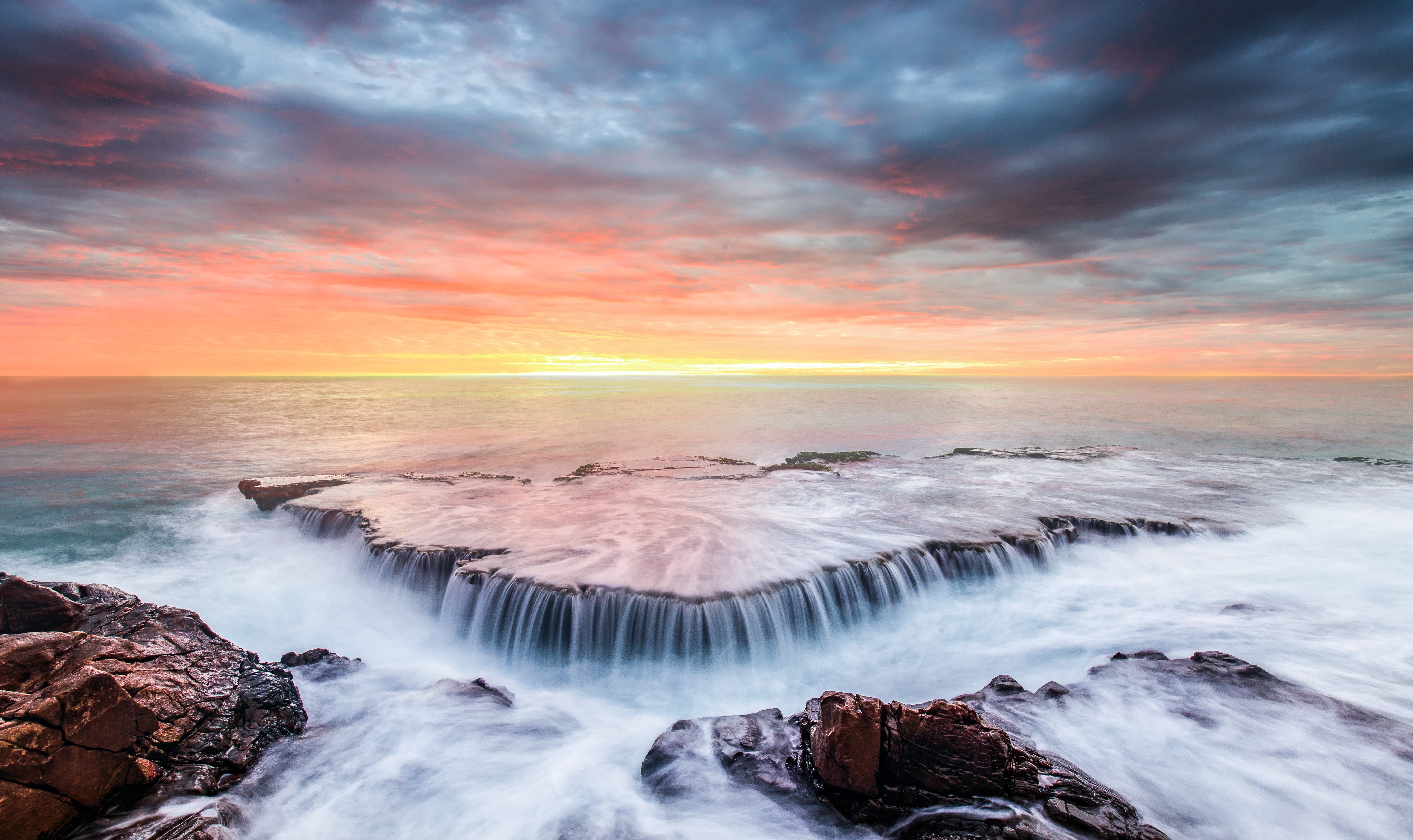 Ocean waves crashing on rocky shore at sunset HD Wallpaper