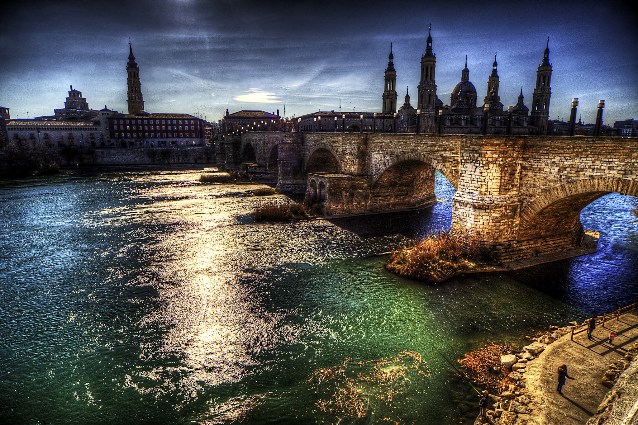 Stone bridge over a river with a cathedral in Zaragoza, Spain HD Wallpaper