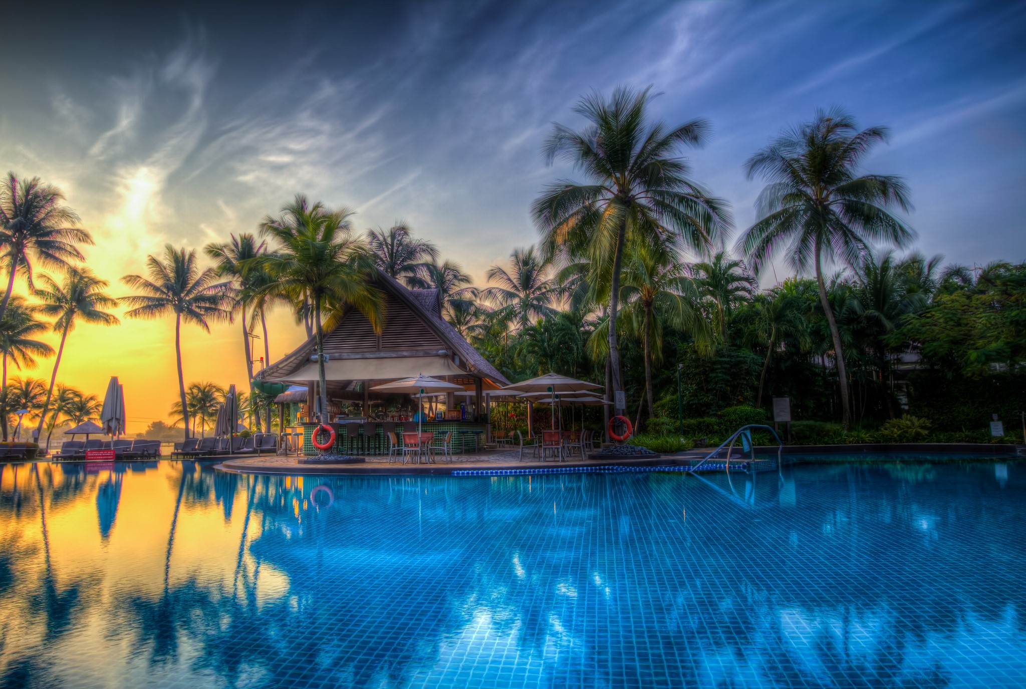 Tropical resort pool bar at sunset with palm trees HD Wallpaper