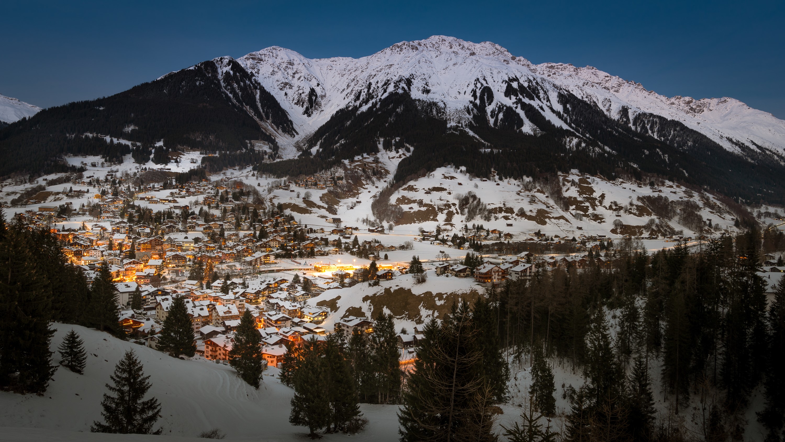 Klosters-Serneus, Switzerland: Snowy mountains and village at dusk HD Wallpaper