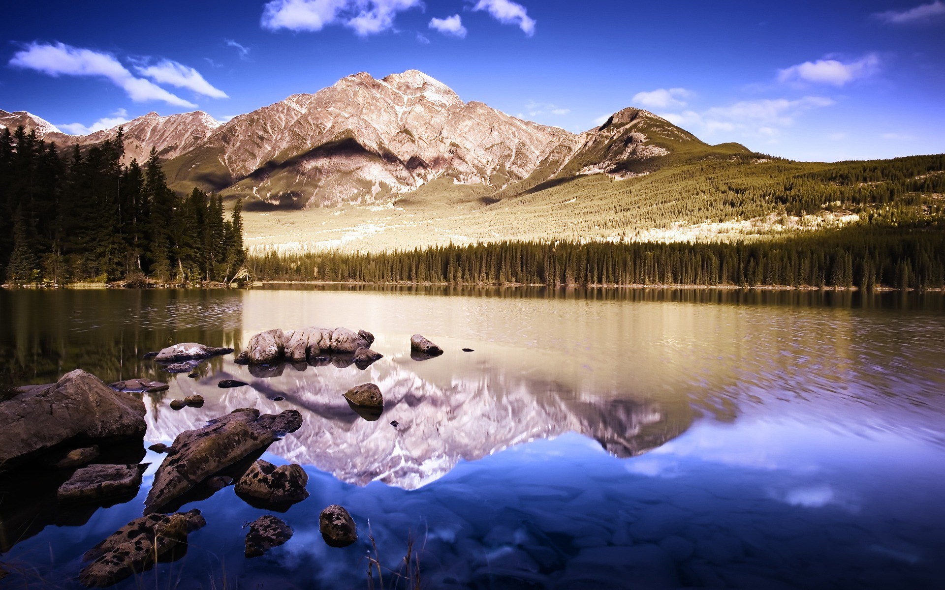 Mountain lake reflection with rocks in foreground HD Wallpaper