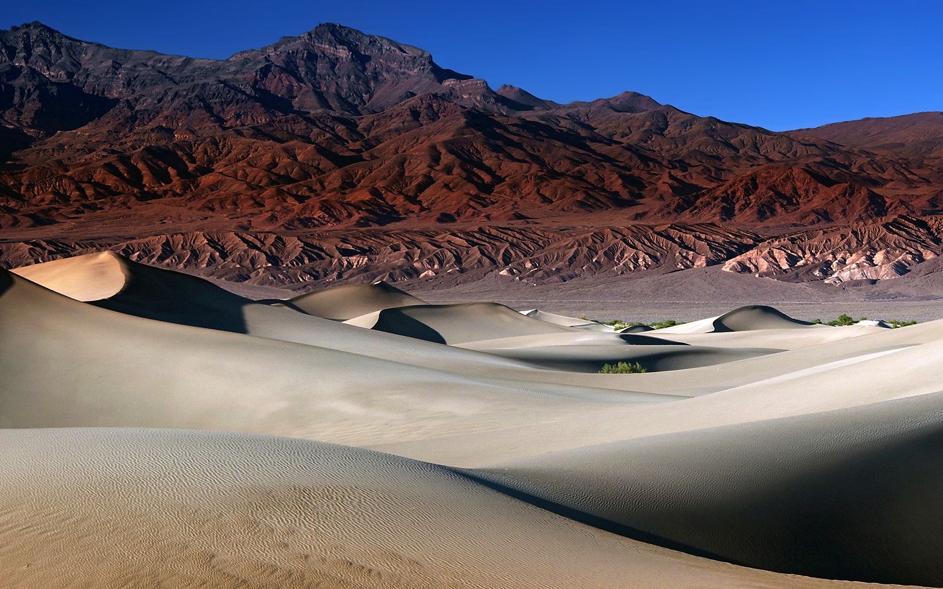 Sand dunes and mountains under a blue sky HD Wallpaper