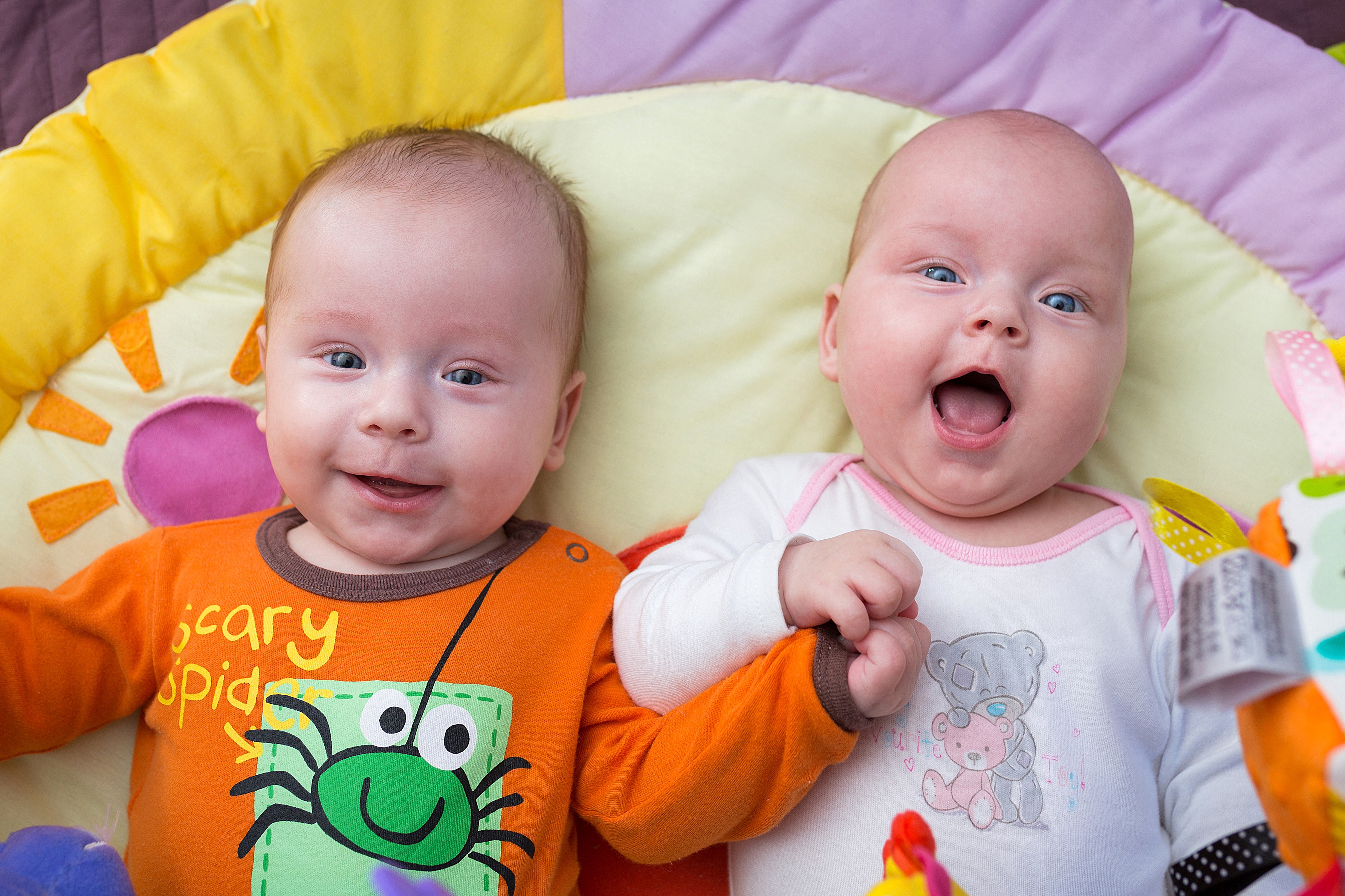Two smiling infants on a playmat HD Wallpaper