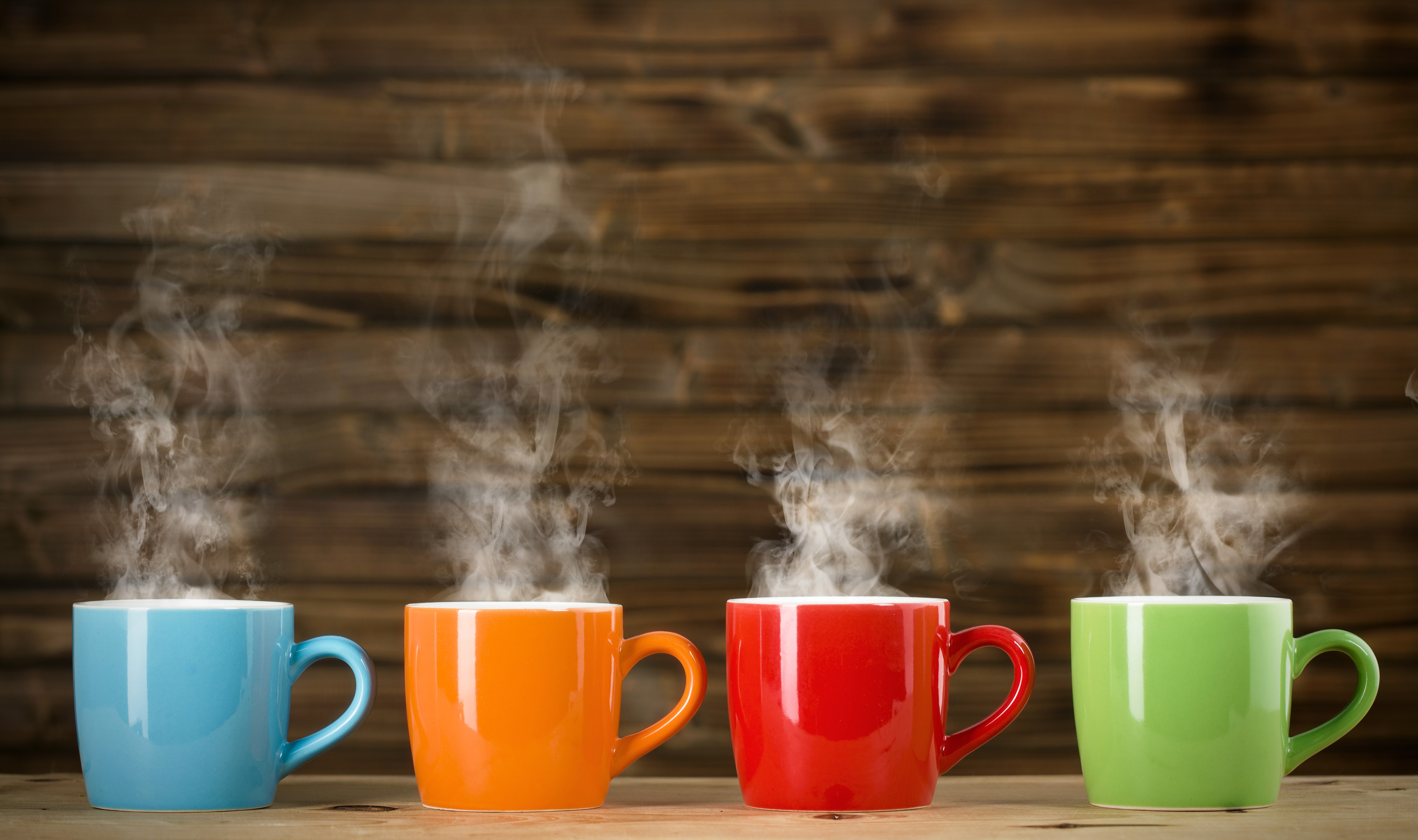 Four steaming mugs of coffee on a wooden table HD Wallpaper