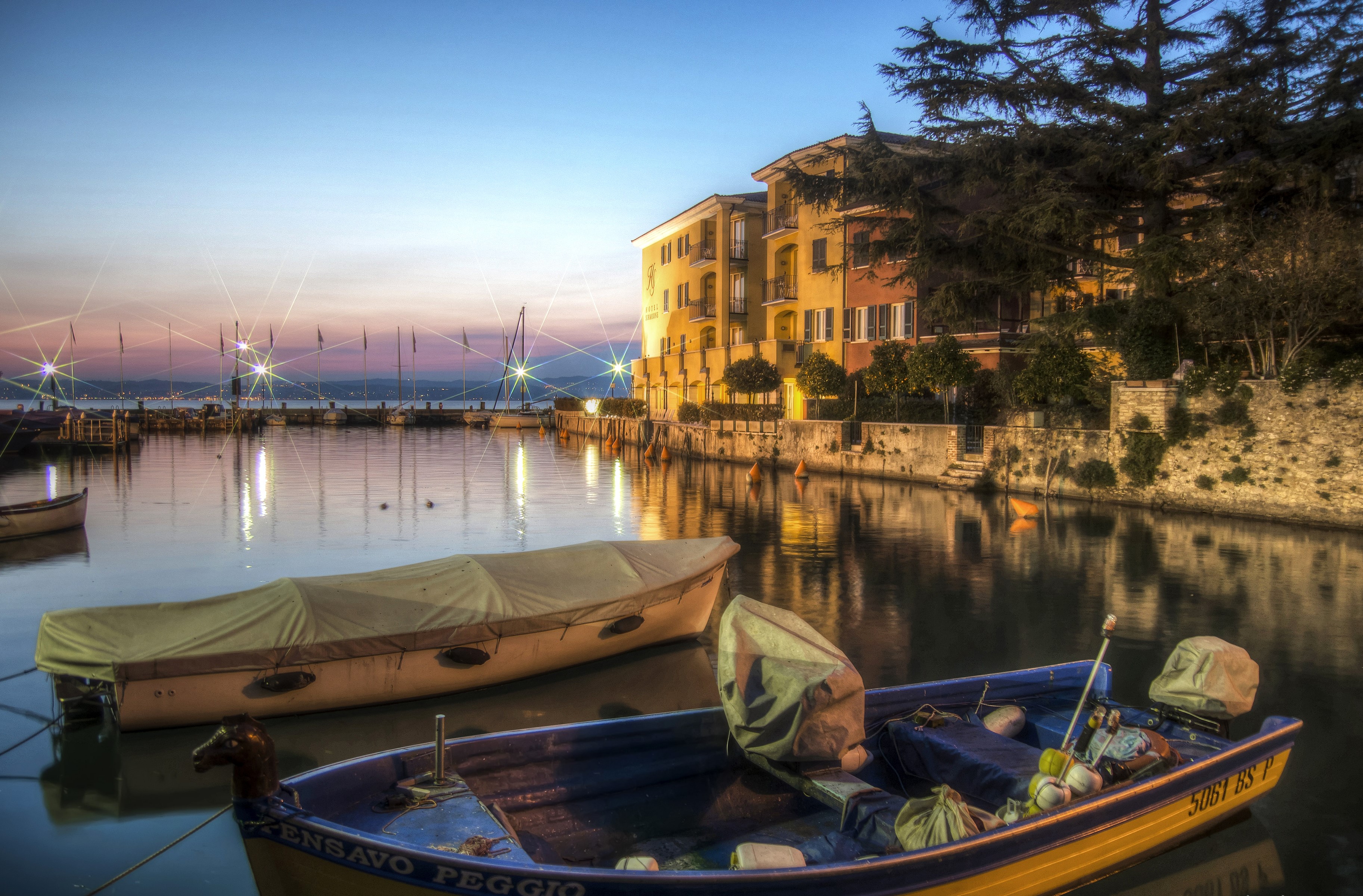 Boats docked in a canal in Sirmione, Lombardy, Italy at dusk HD Wallpaper