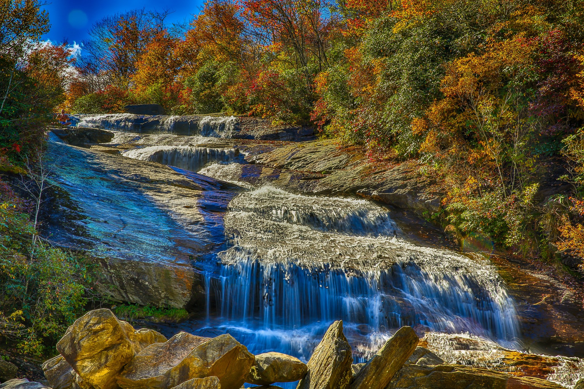Waterfall cascading over rocks with autumn foliage HD Wallpaper