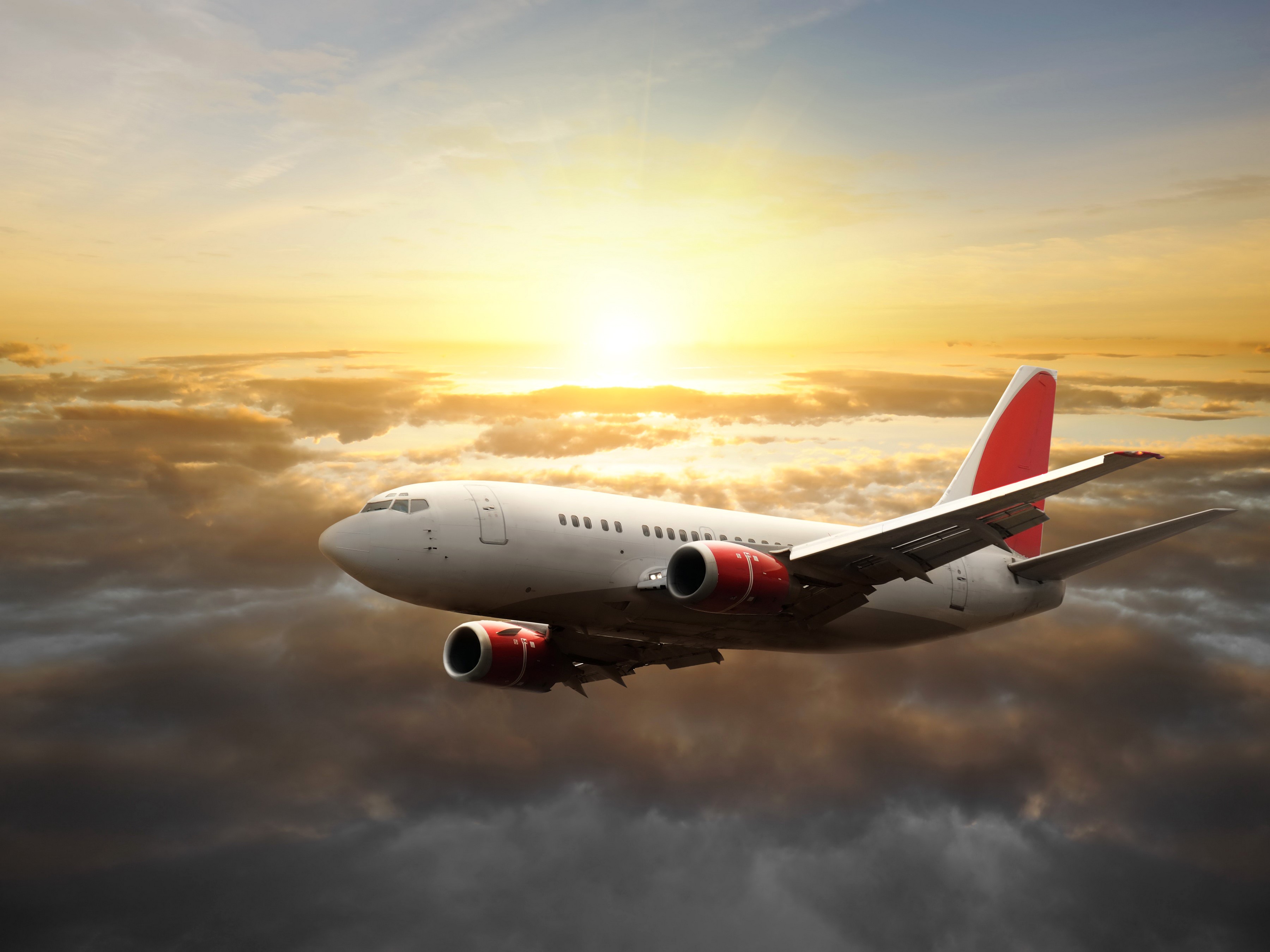 Airplane flying through clouds at sunset HD Wallpaper