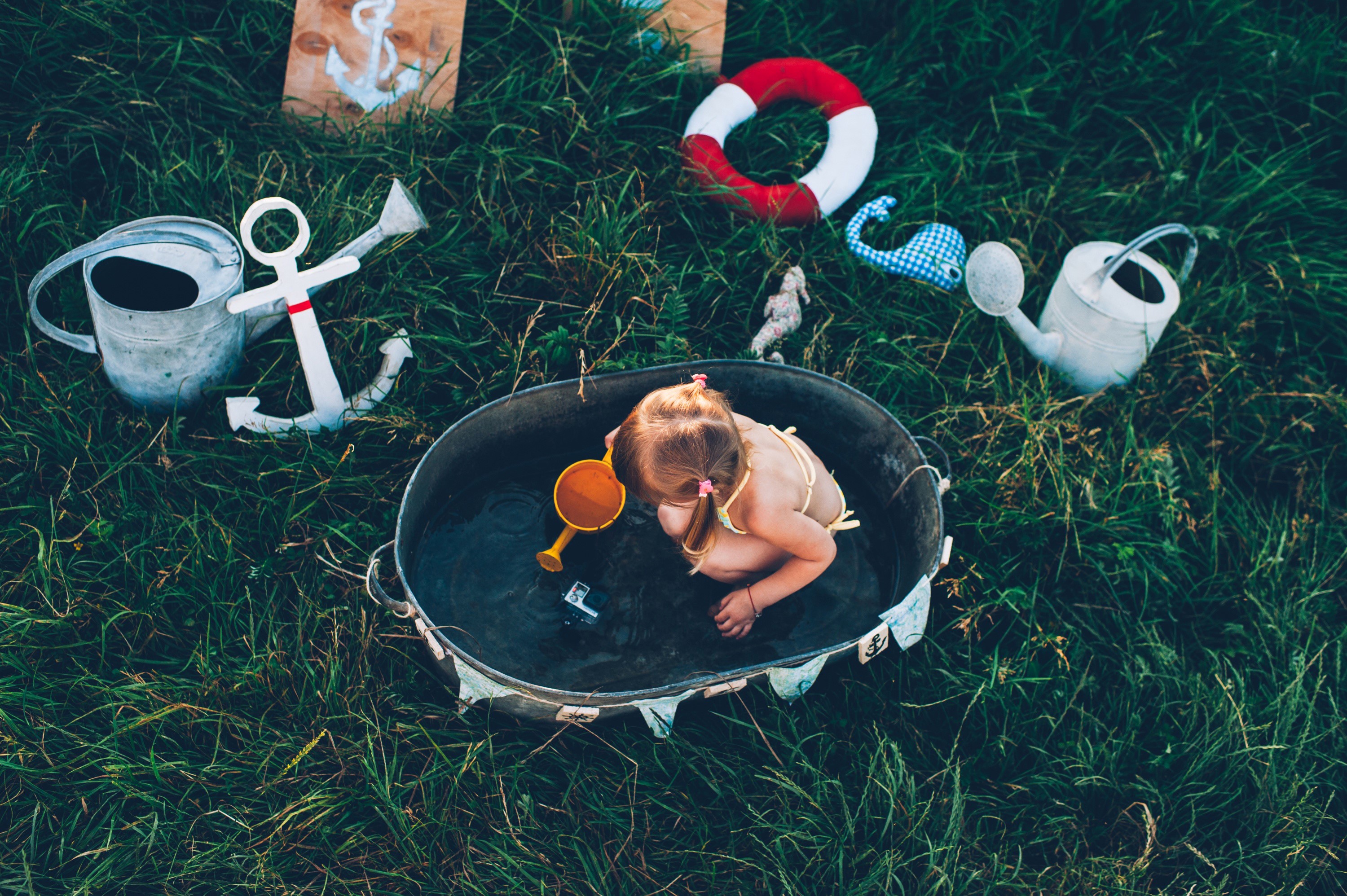 Little girl playing in a tub with nautical toys HD Wallpaper