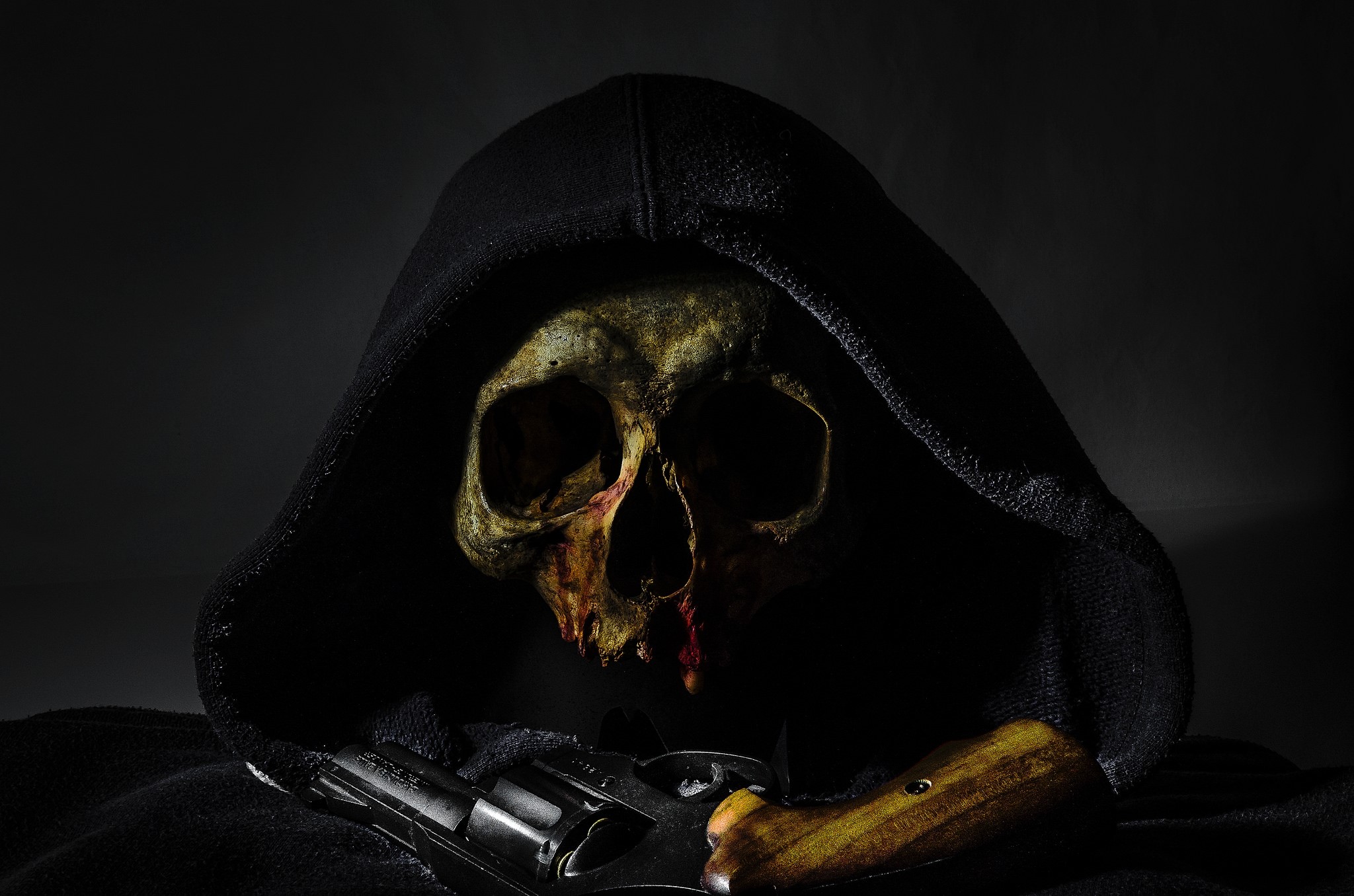 Skull in a hood with a revolver HD Wallpaper