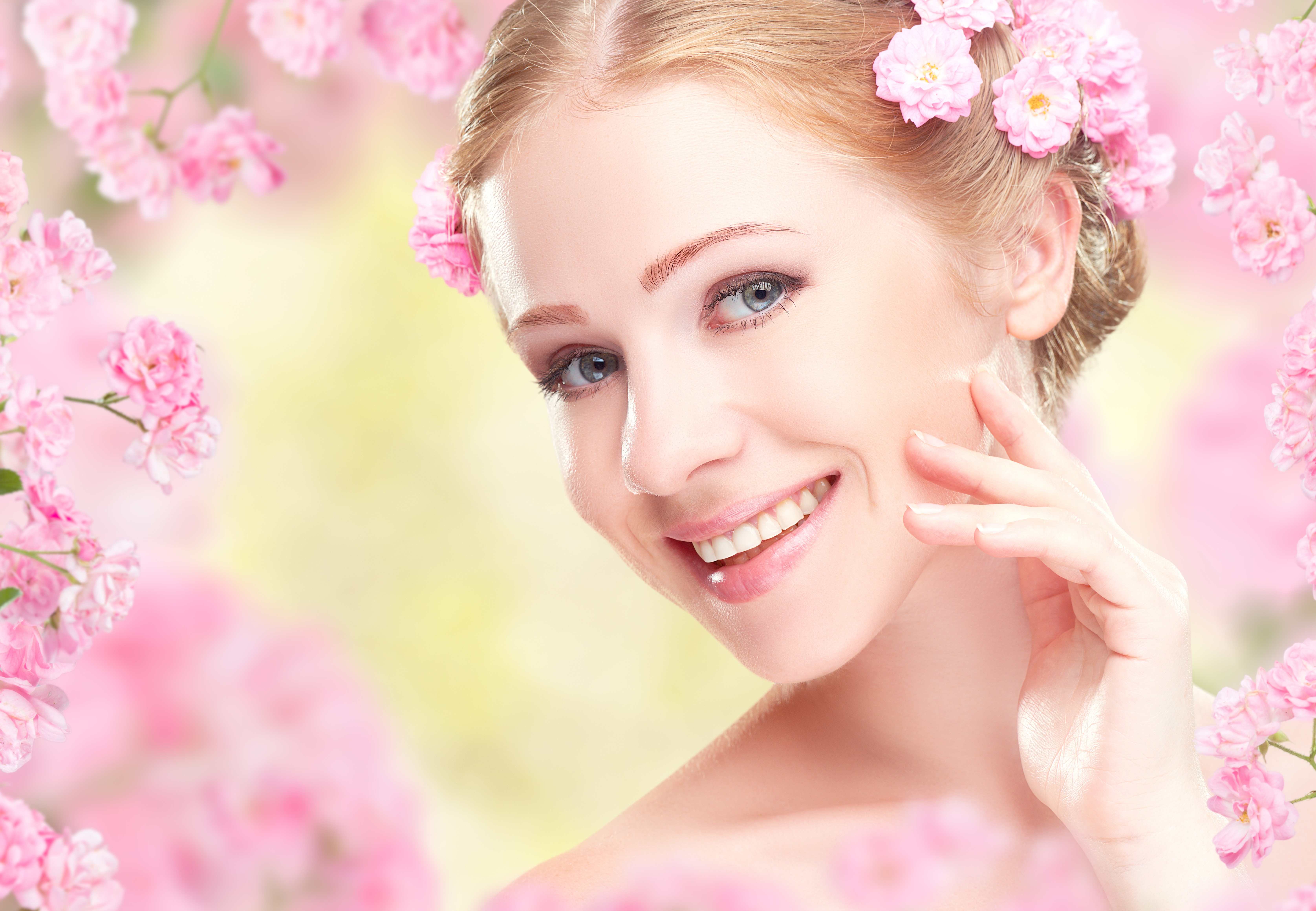 Blonde girl with pink flowers in her hair smiling HD Wallpaper
