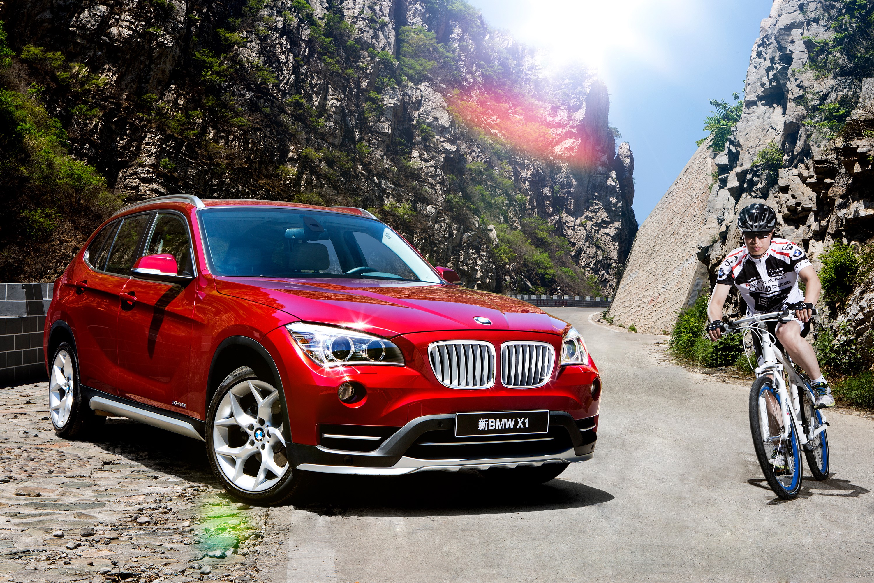 Red BMW X1 and cyclist on mountain road HD Wallpaper
