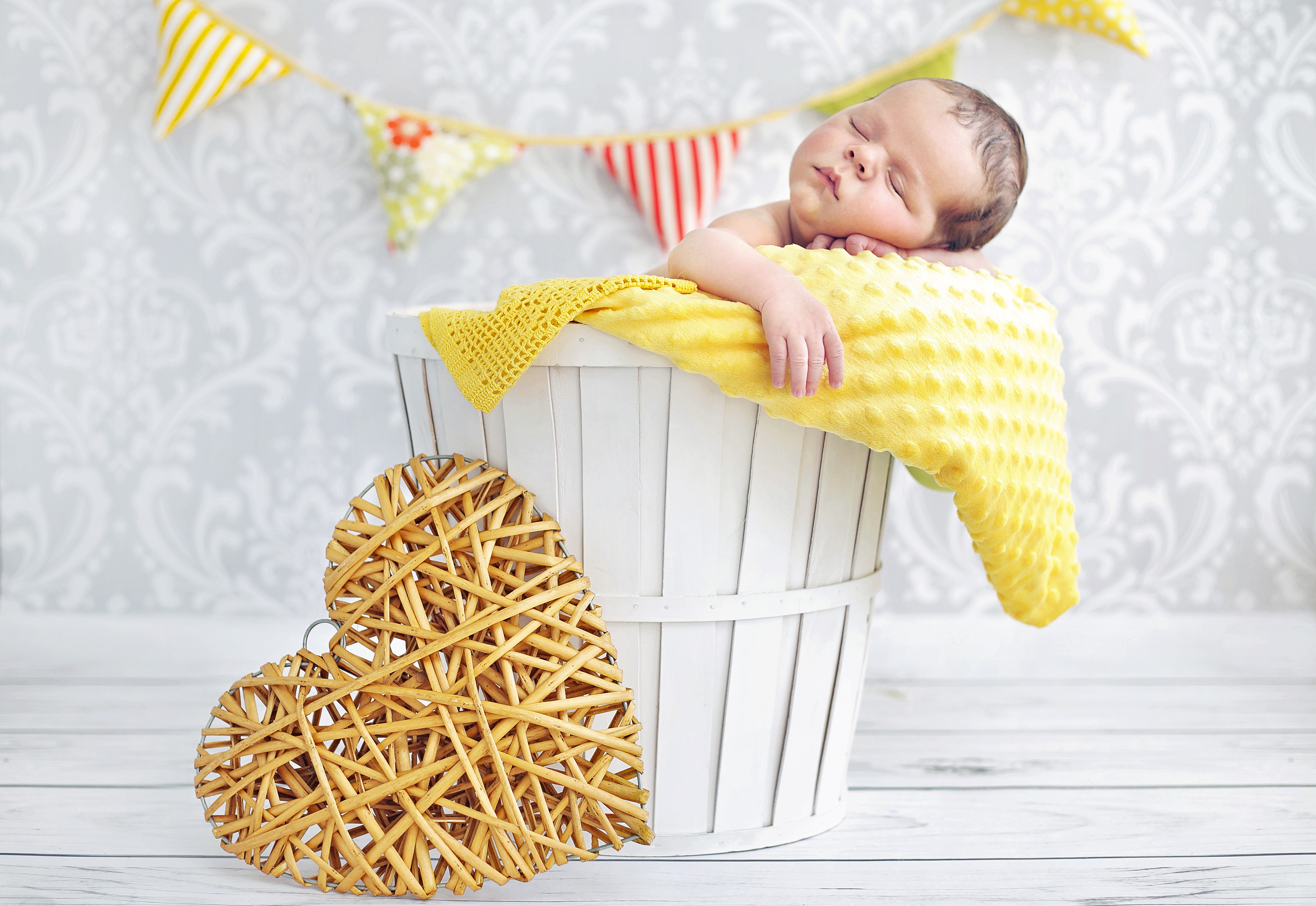 Newborn baby sleeping in a basket with a heart decoration HD Wallpaper