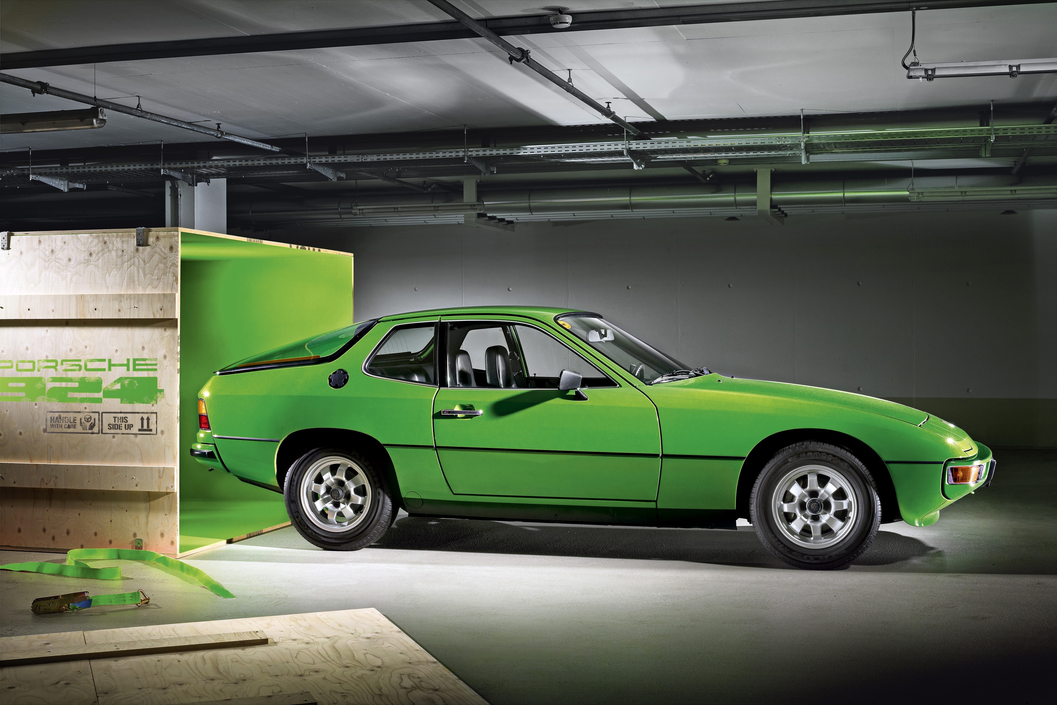Green Porsche 924 parked next to a wooden crate HD Wallpaper