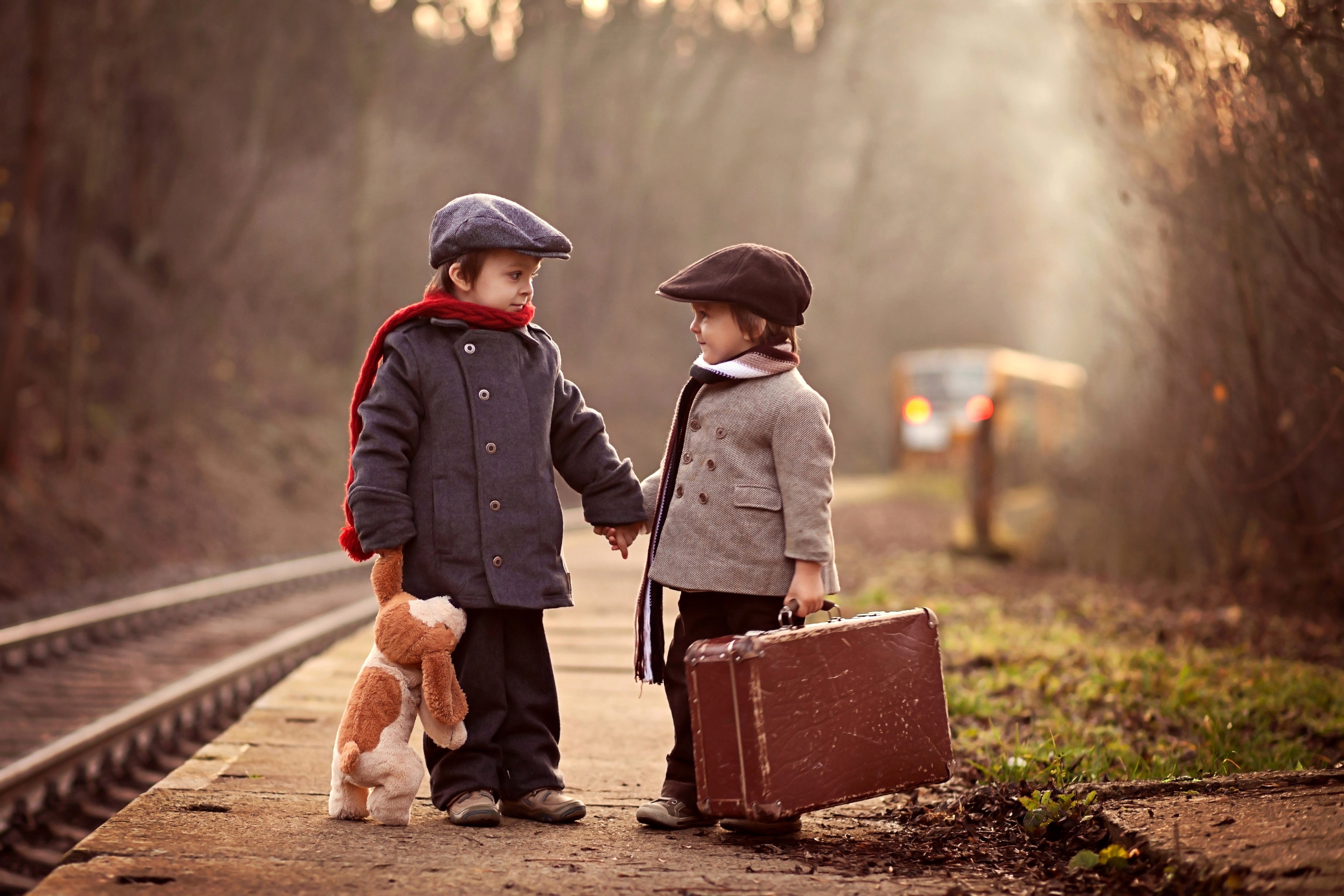 Two boys with suitcase and toy on train platform HD Wallpaper