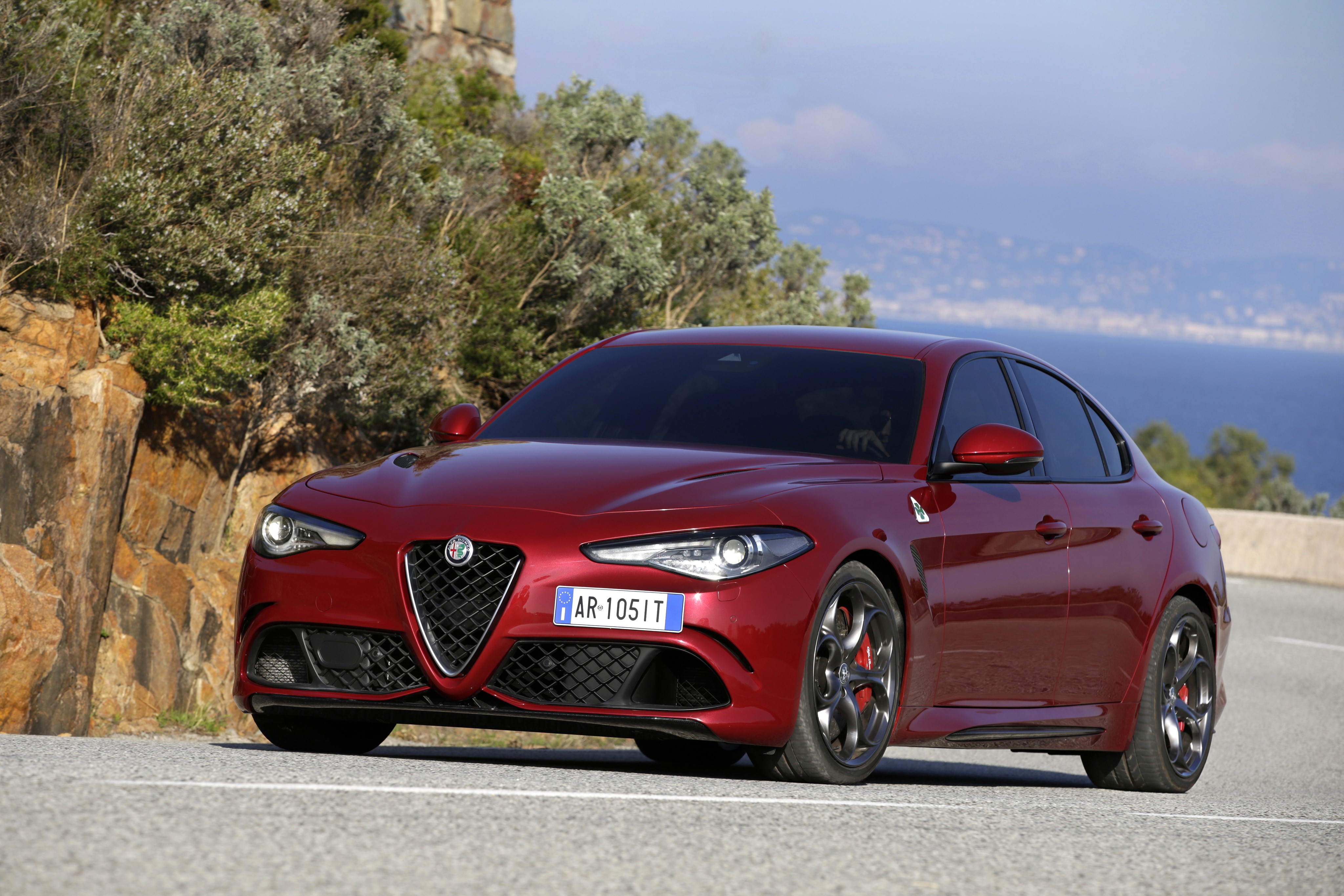 Red Alfa Romeo Giulia Quadrifoglio driving on a coastal road HD Wallpaper
